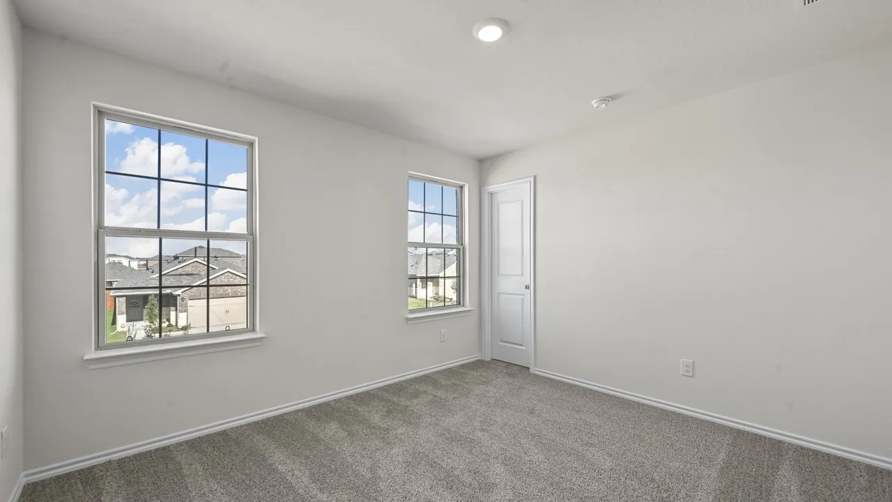 Recessed ceiling lighting, carpeted flooring, two windows with grids, and a solid interior door
