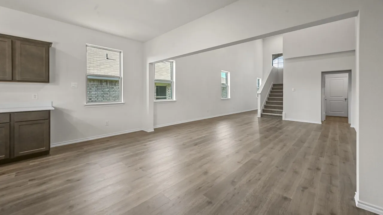 Spacious open-concept interior with wood-finish flooring, white walls, and abundant natural light from multiple windows