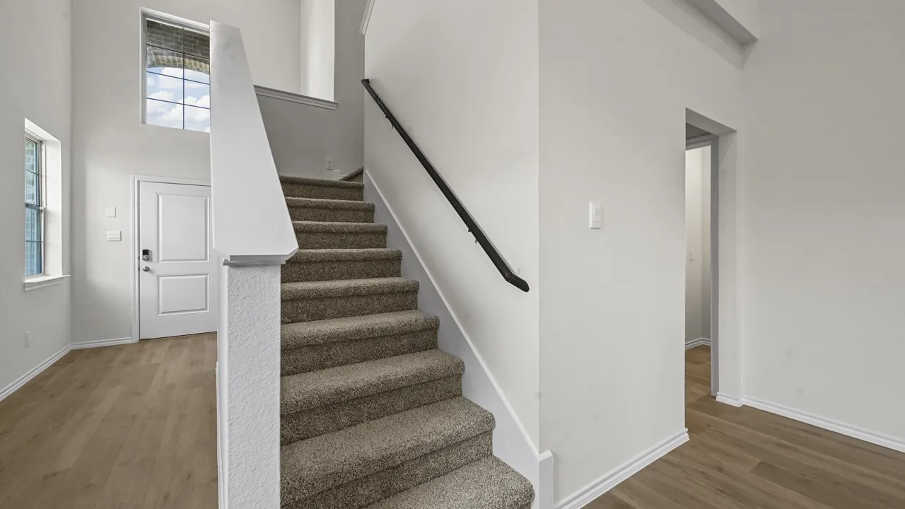 Two-story entryway with wood-finish flooring, a carpeted staircase, and high ceilings