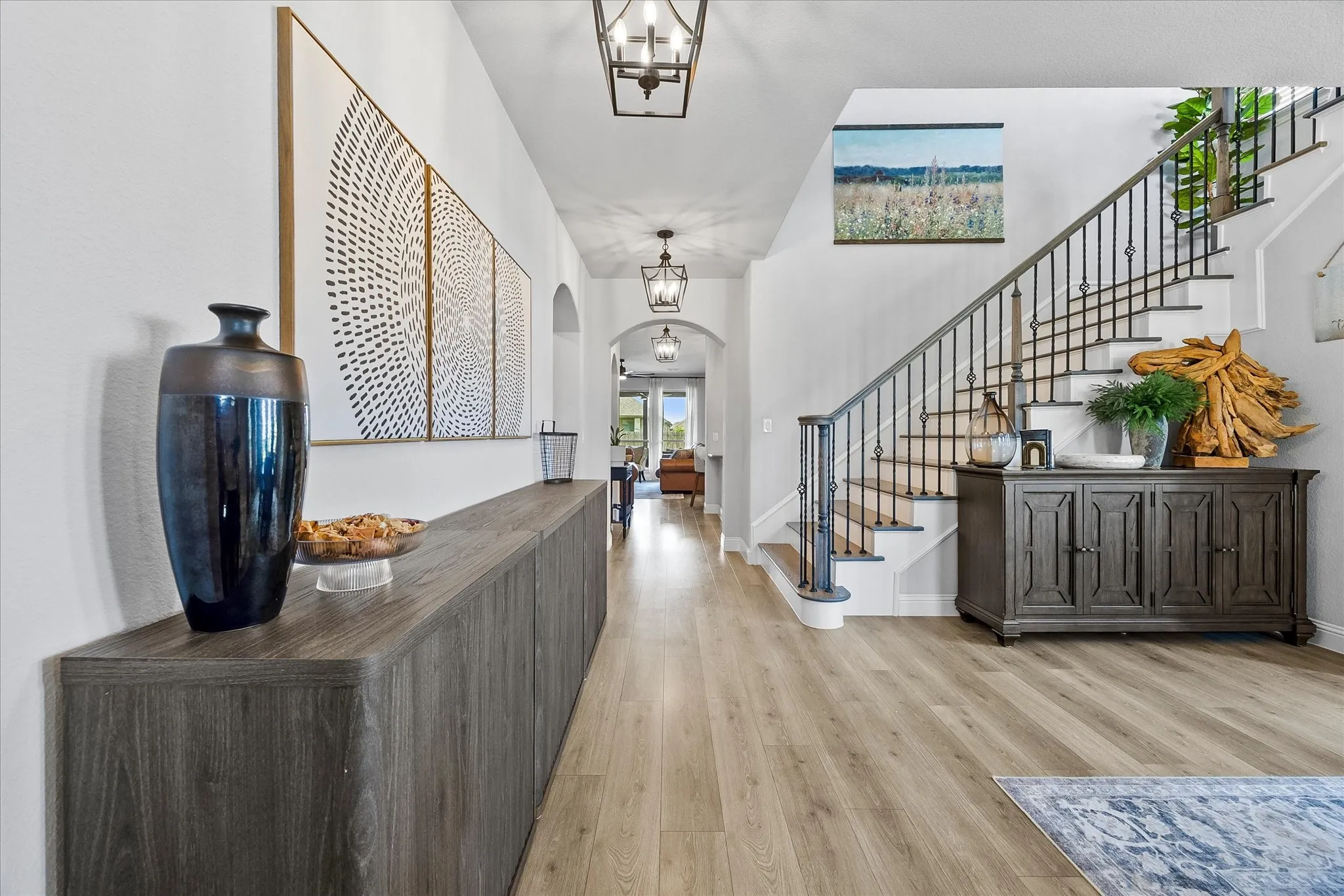 Entryway featuring wood-finish flooring, a grand staircase with wrought iron balusters, a built-in console, and recessed lighting