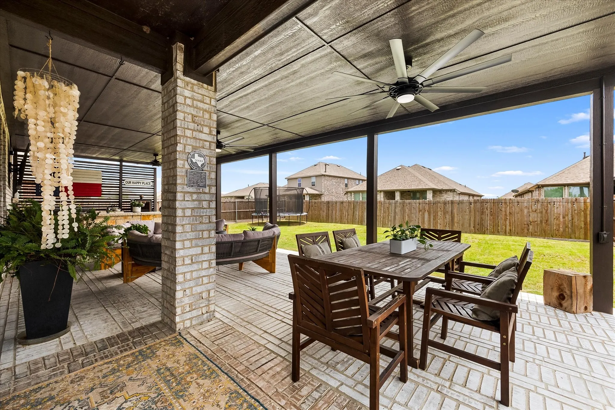 Covered patio featuring a brick accent column and wood-look ceiling with a ceiling fan