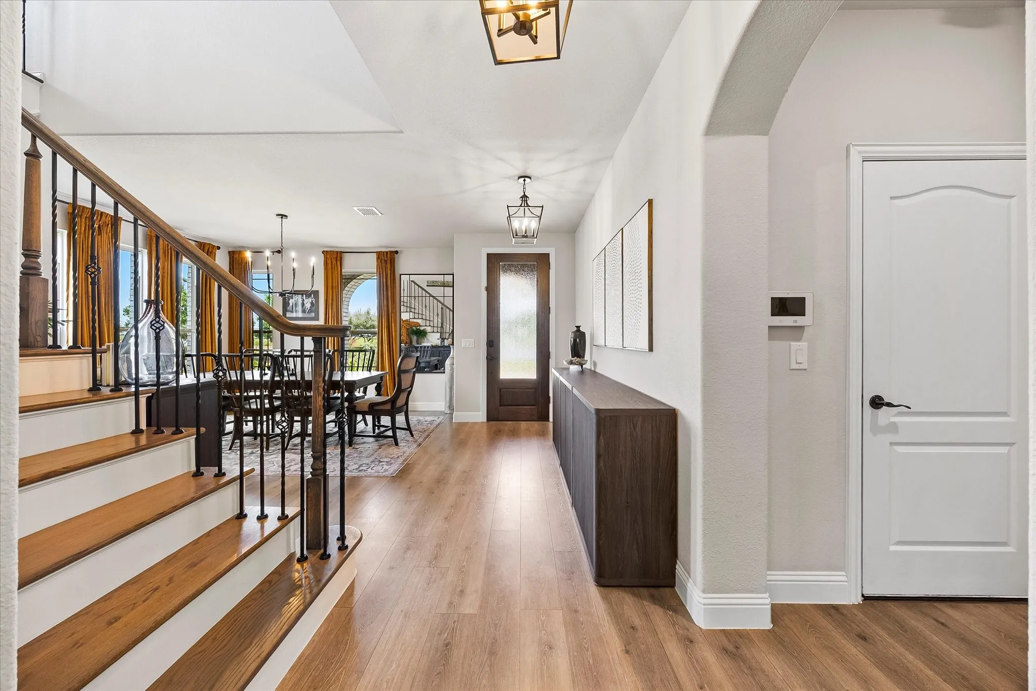 Entryway featuring wood-finish flooring, a contemporary dining area, and a staircase with wood treads and iron balusters