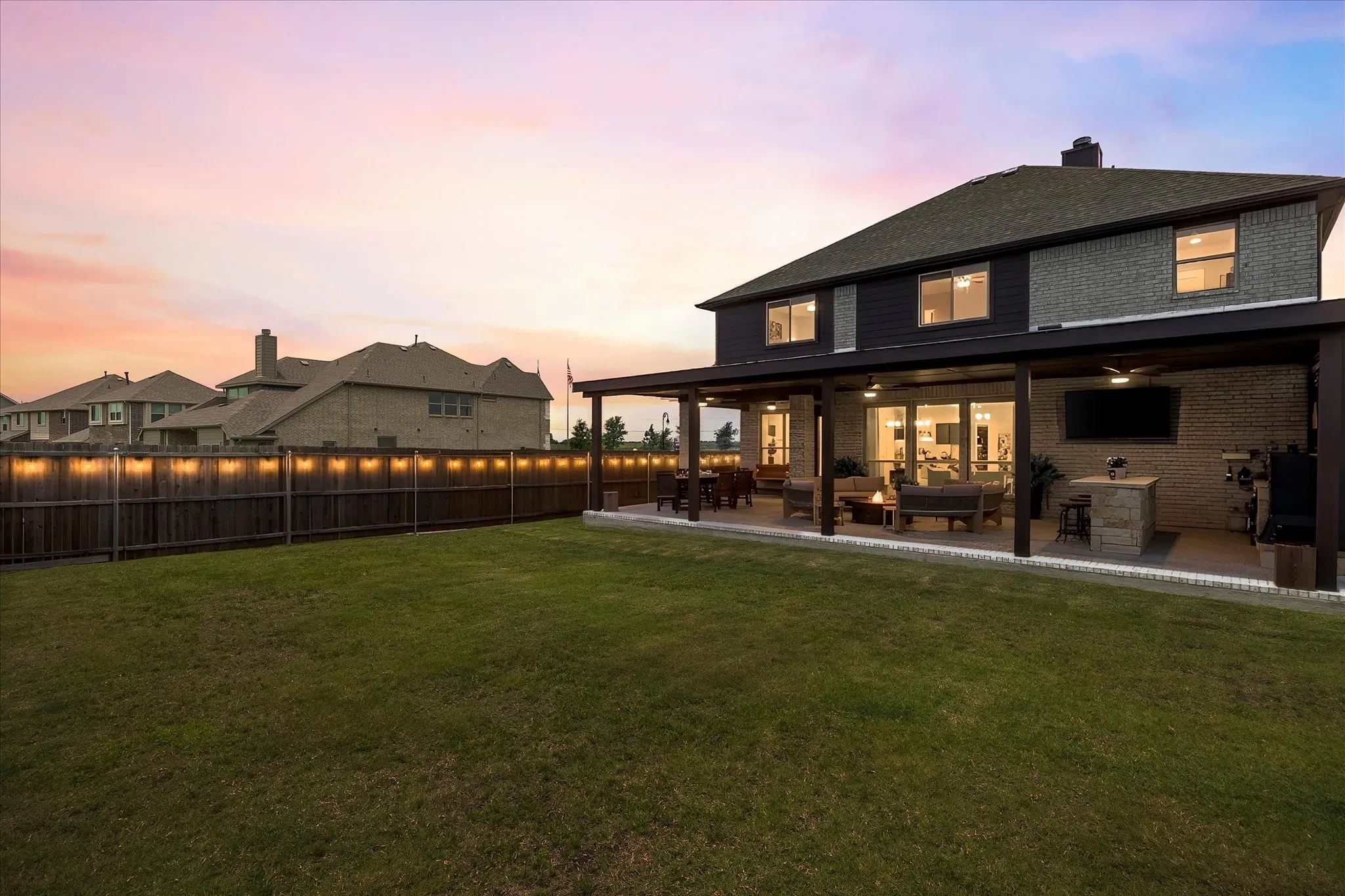Expansive backyard featuring a manicured lawn, full privacy fencing, and a covered patio