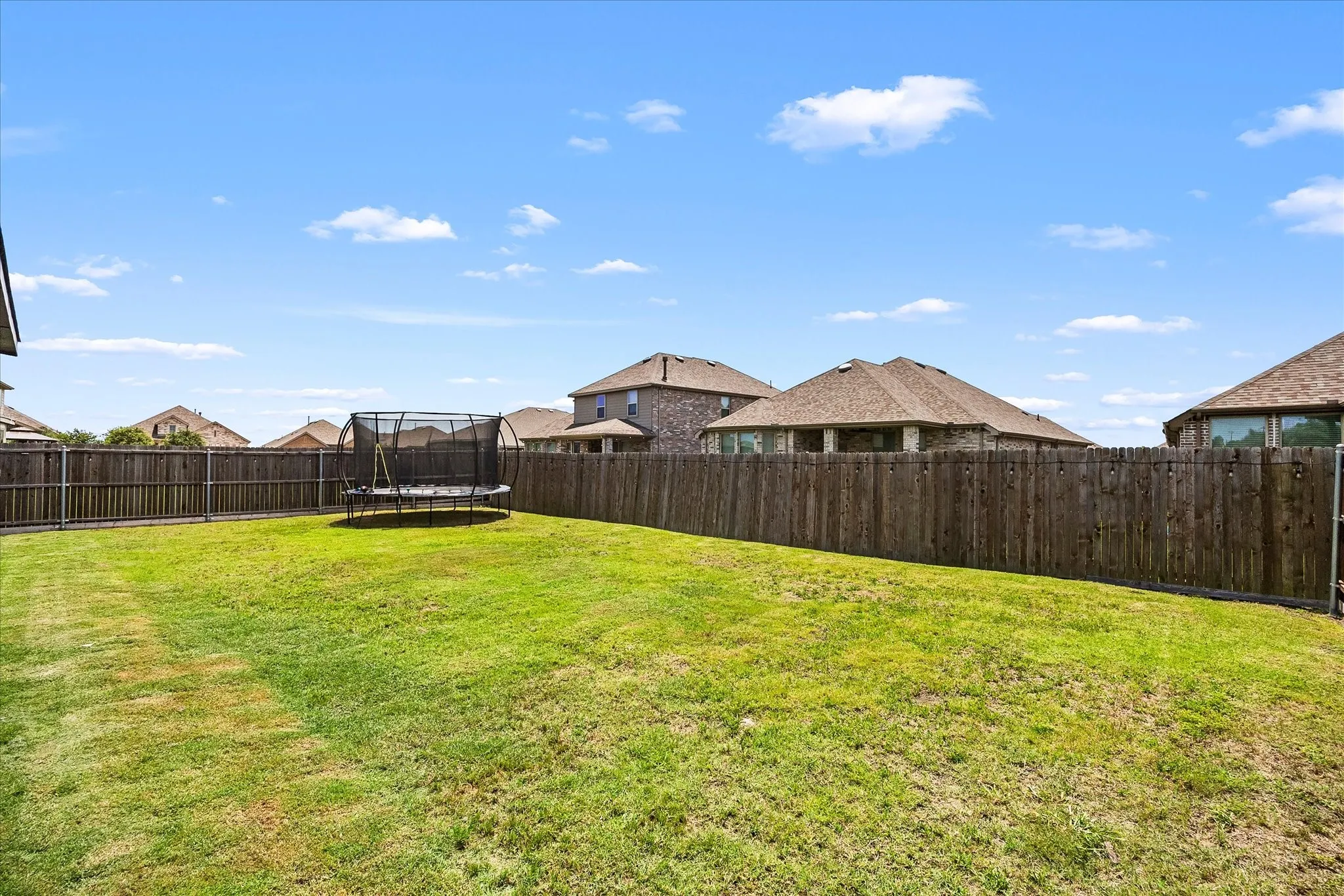 Expansive grassy yard with full wood privacy fencing