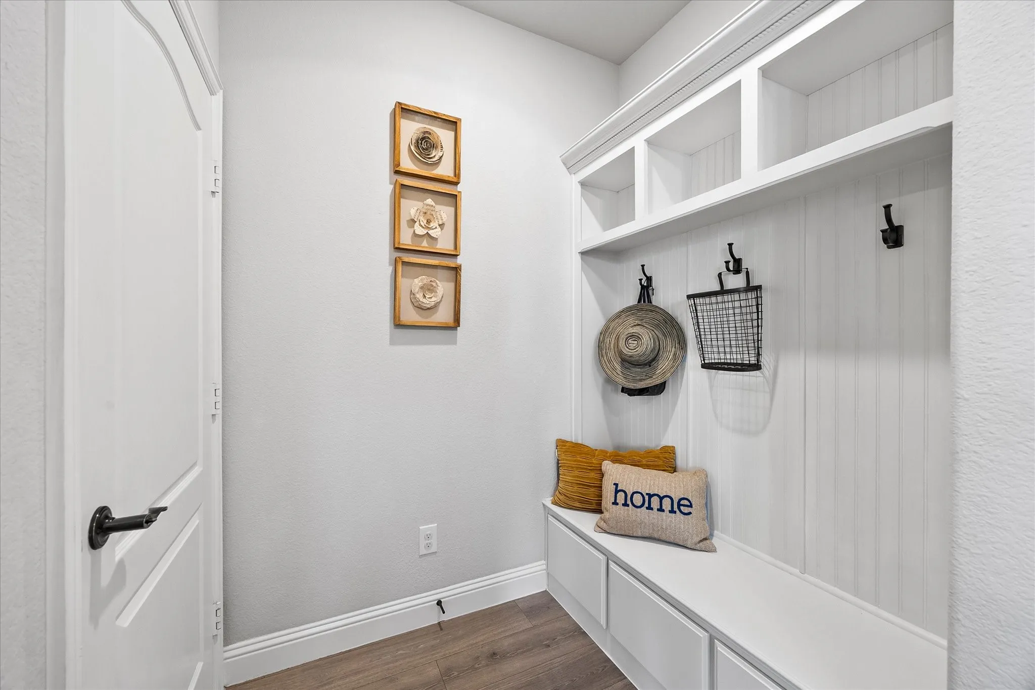 Built-in mudroom bench with cubbies, upper shelving, and beadboard paneling