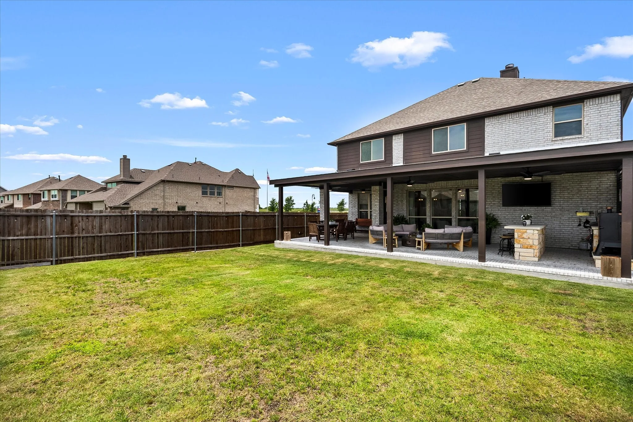 Expansive backyard featuring a covered patio with recessed lighting, ceiling fans, and an outdoor television