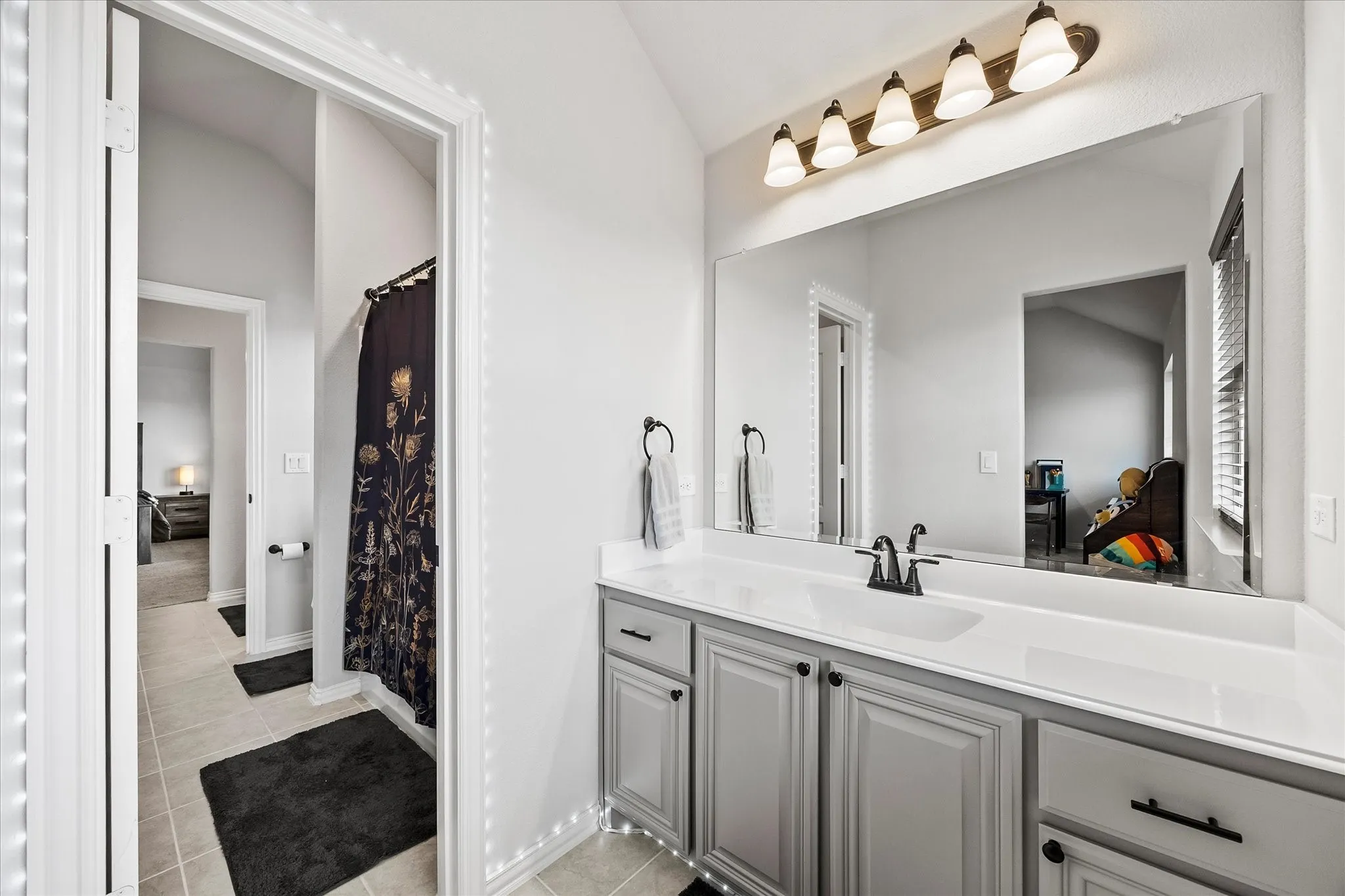 Vanity featuring a white countertop, undermount sink, and dark-finished faucet