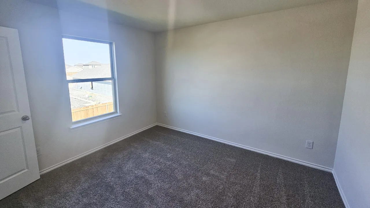 Neutral wall tones, gray carpeting, and a window with white trim