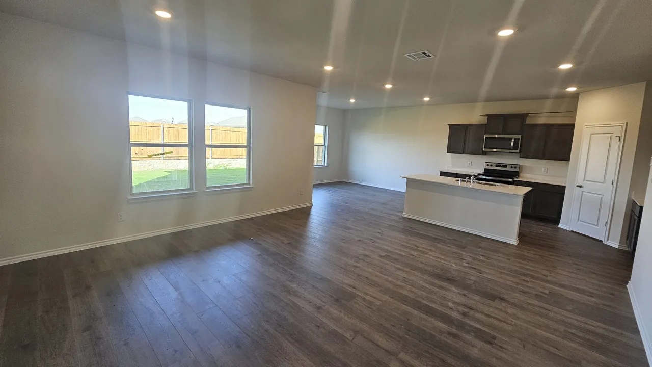 Spacious open concept living area featuring wood-finish flooring, recessed lighting, and a kitchen island with built-in cabinetry