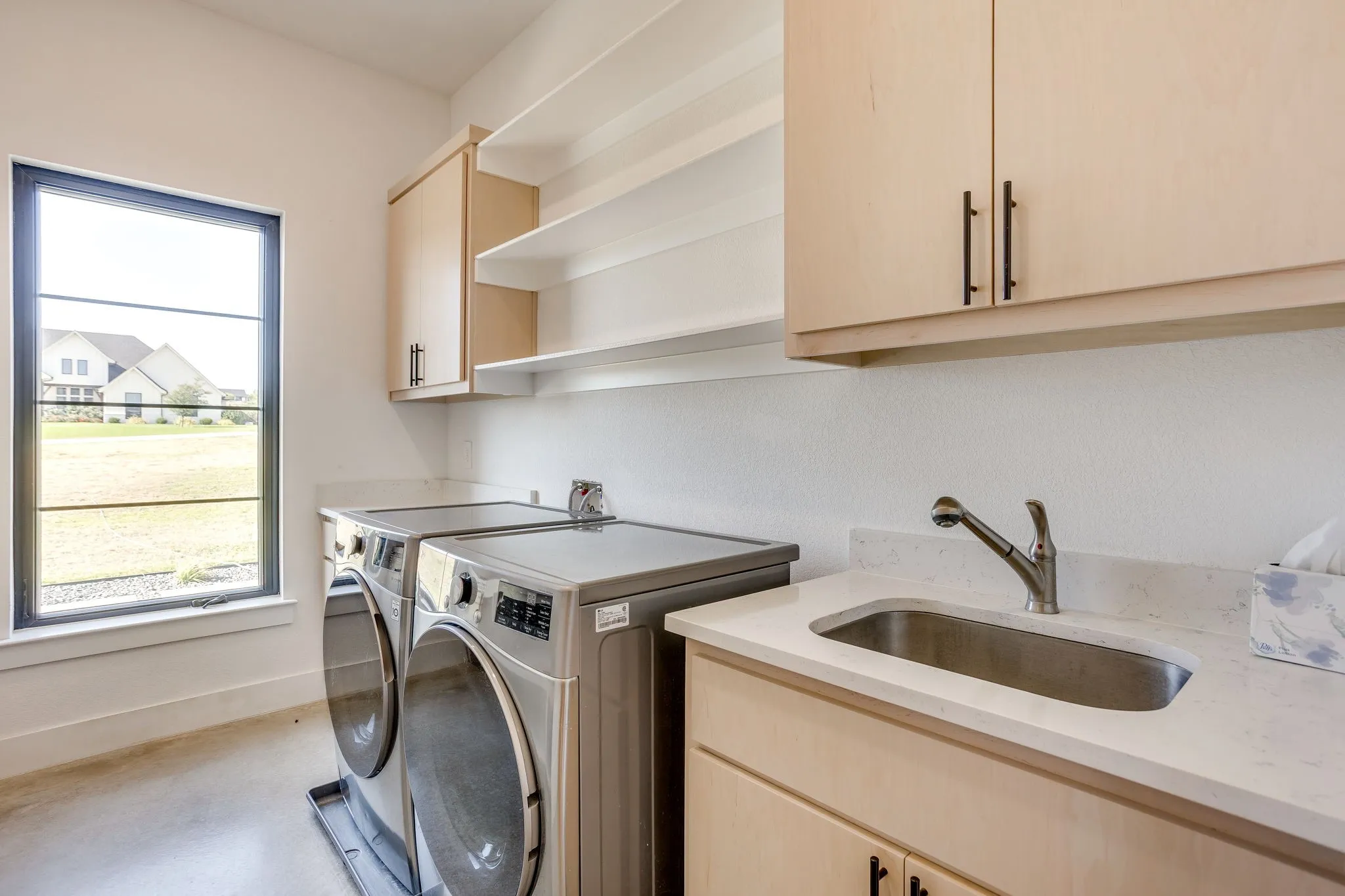 The extra spacious laundry room includes a sink, shelving, extra storage, folding table and drip dry area.