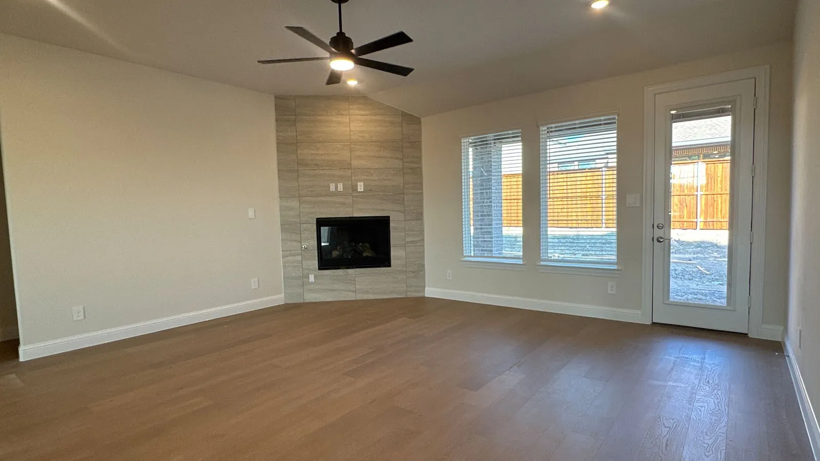 Wood-finish flooring, recessed lighting, and a modern fireplace with a tiled surround