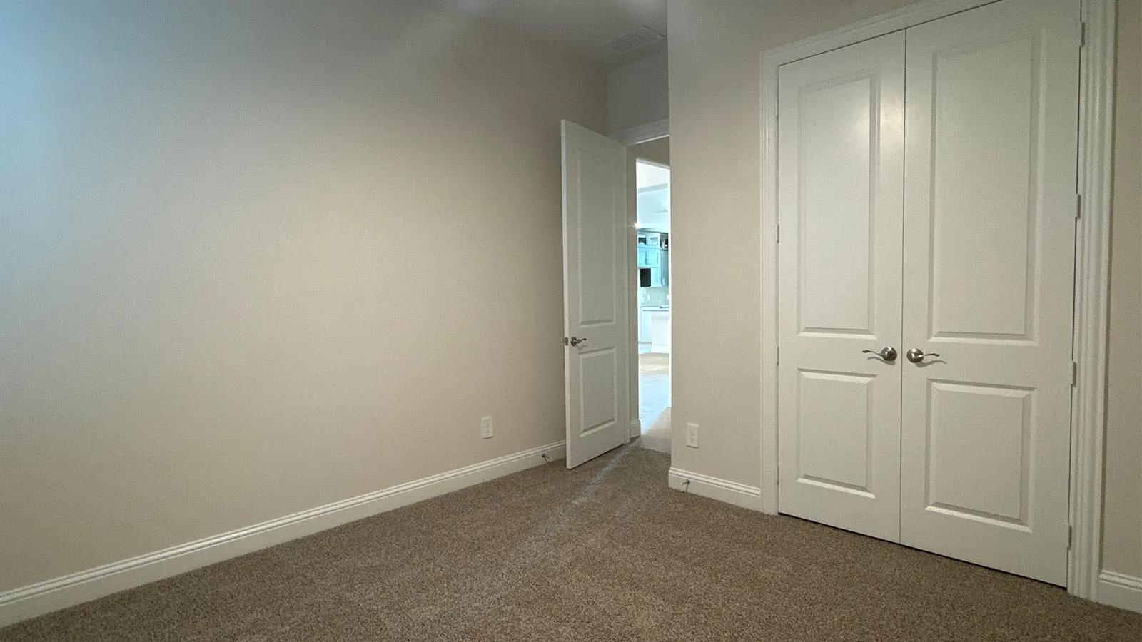 Neutral tone walls, carpeting, white paneled doors, and brushed nickel hardware