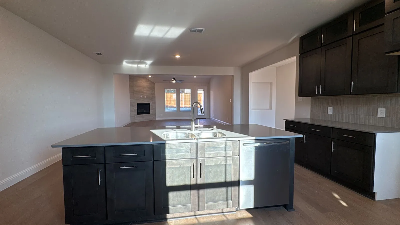 Kitchen island with an undermount sink, a dishwasher, and dark wood-finish cabinetry