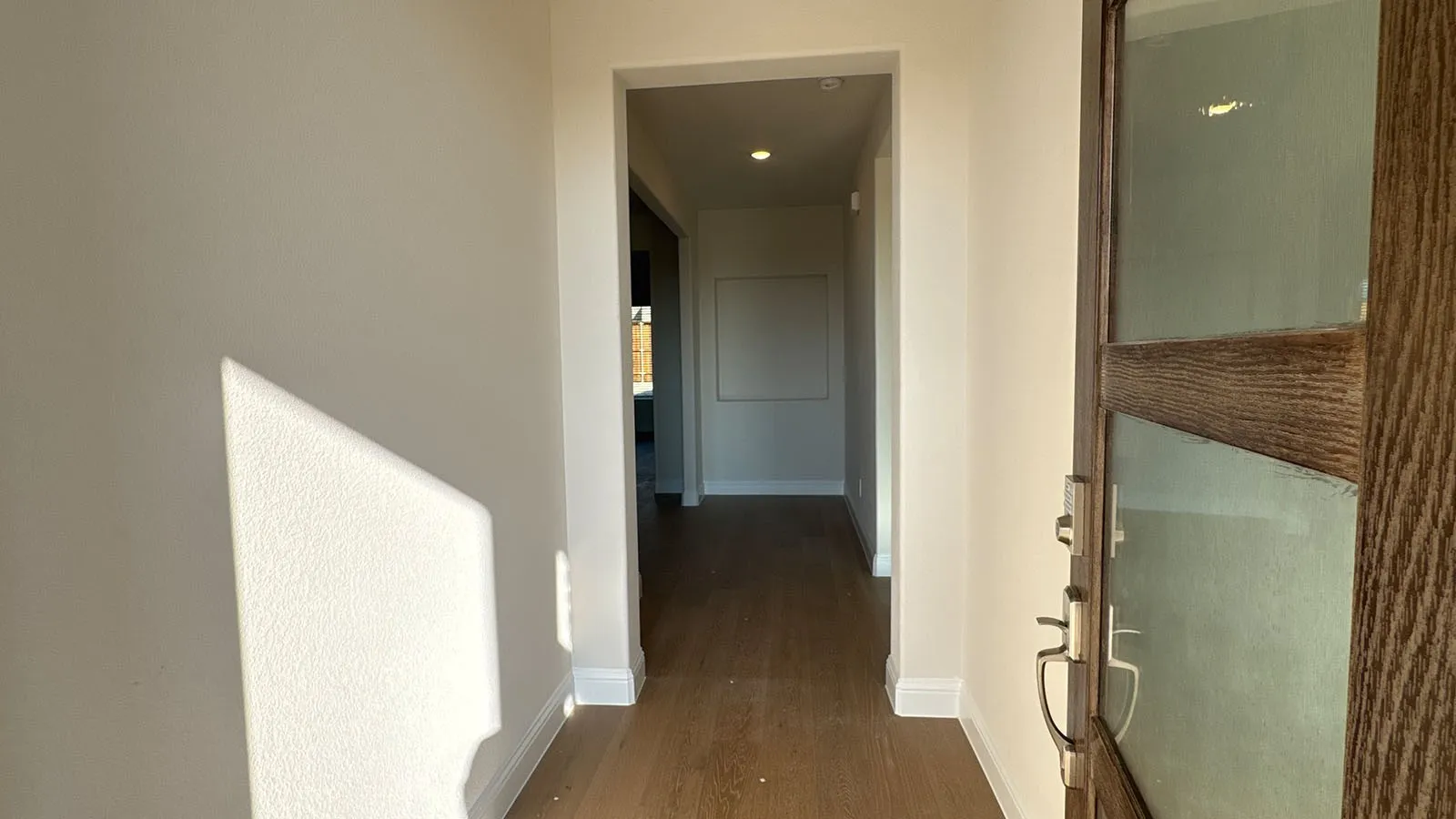 Wood-finish flooring throughout, recessed lighting, and a solid wood entry door with frosted glass panels