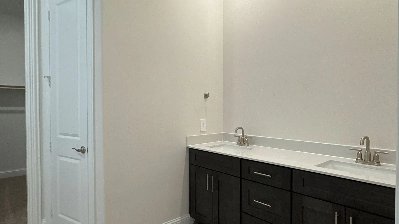 Dual vanity with white undermount sinks, brushed nickel faucets, and dark wood-finish cabinetry