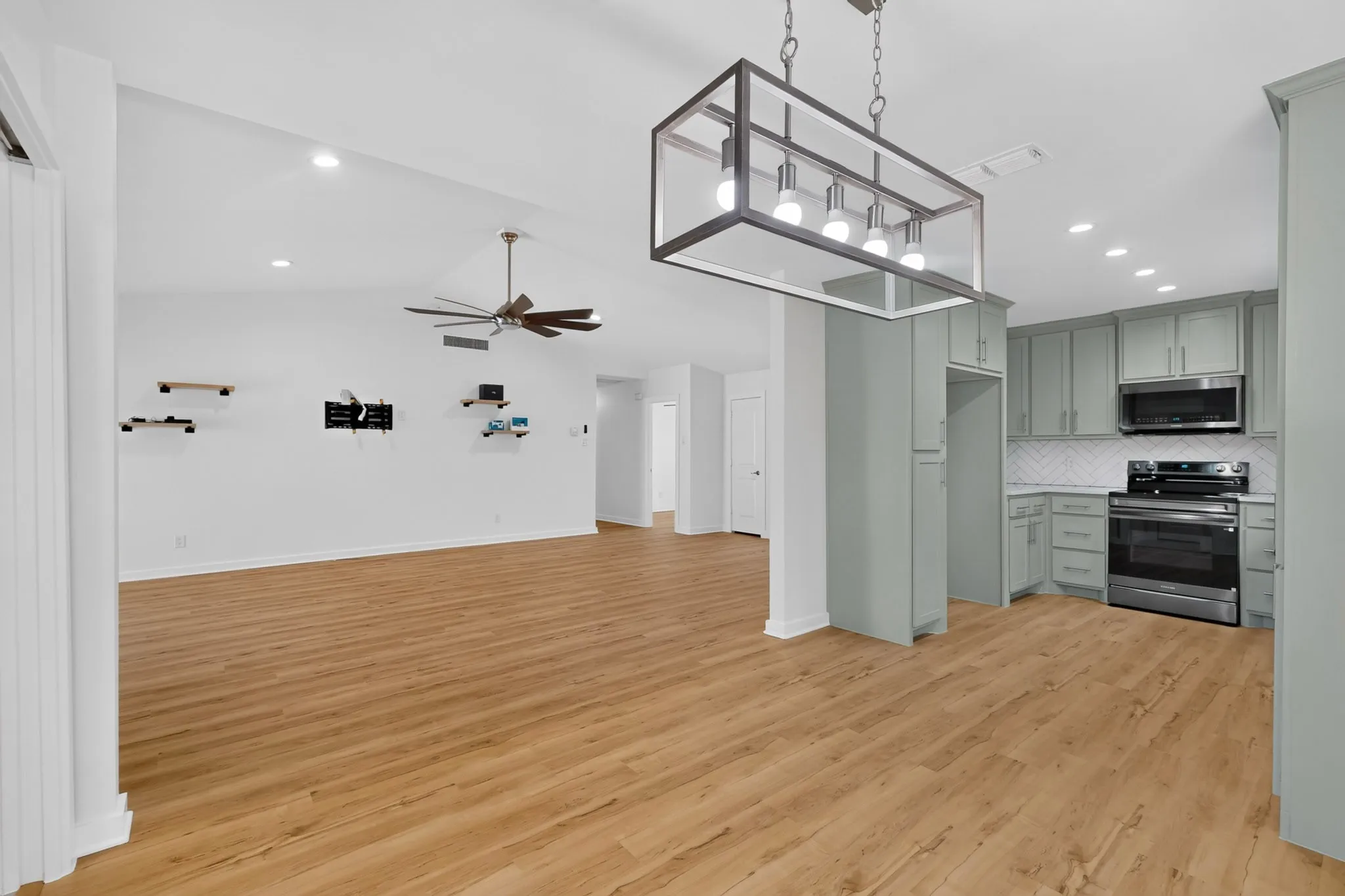 Vaulted ceiling, recessed lighting, wood-finish flooring, kitchen with light-toned cabinetry, stainless steel appliances