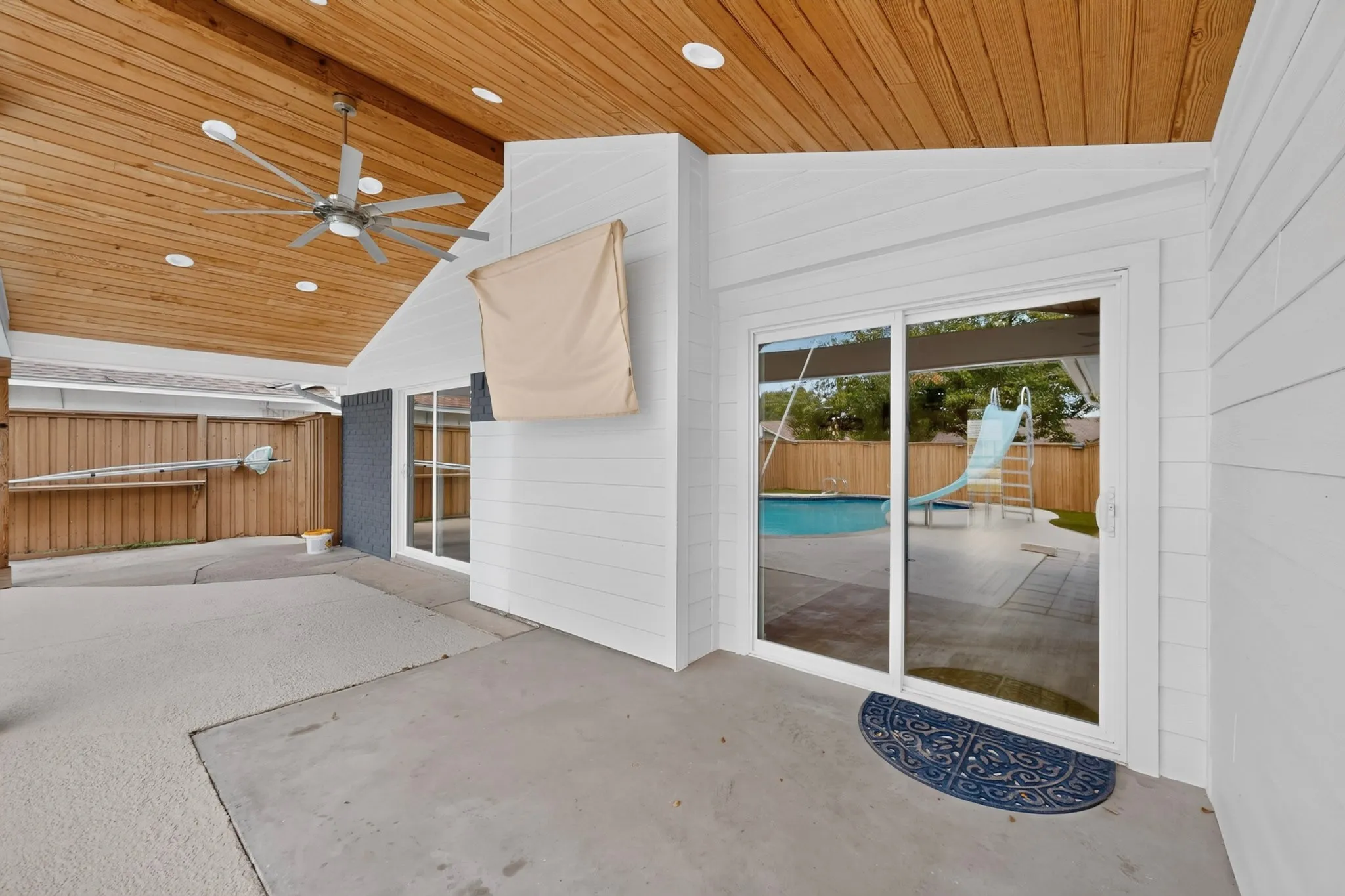 Covered patio with wood-paneled ceiling, recessed lighting, and ceiling fan
