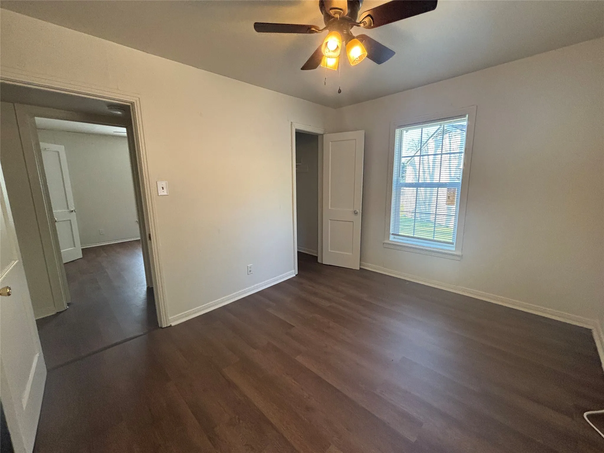 White-painted walls and trim, wood-finish flooring, and a ceiling fan with integrated lighting
