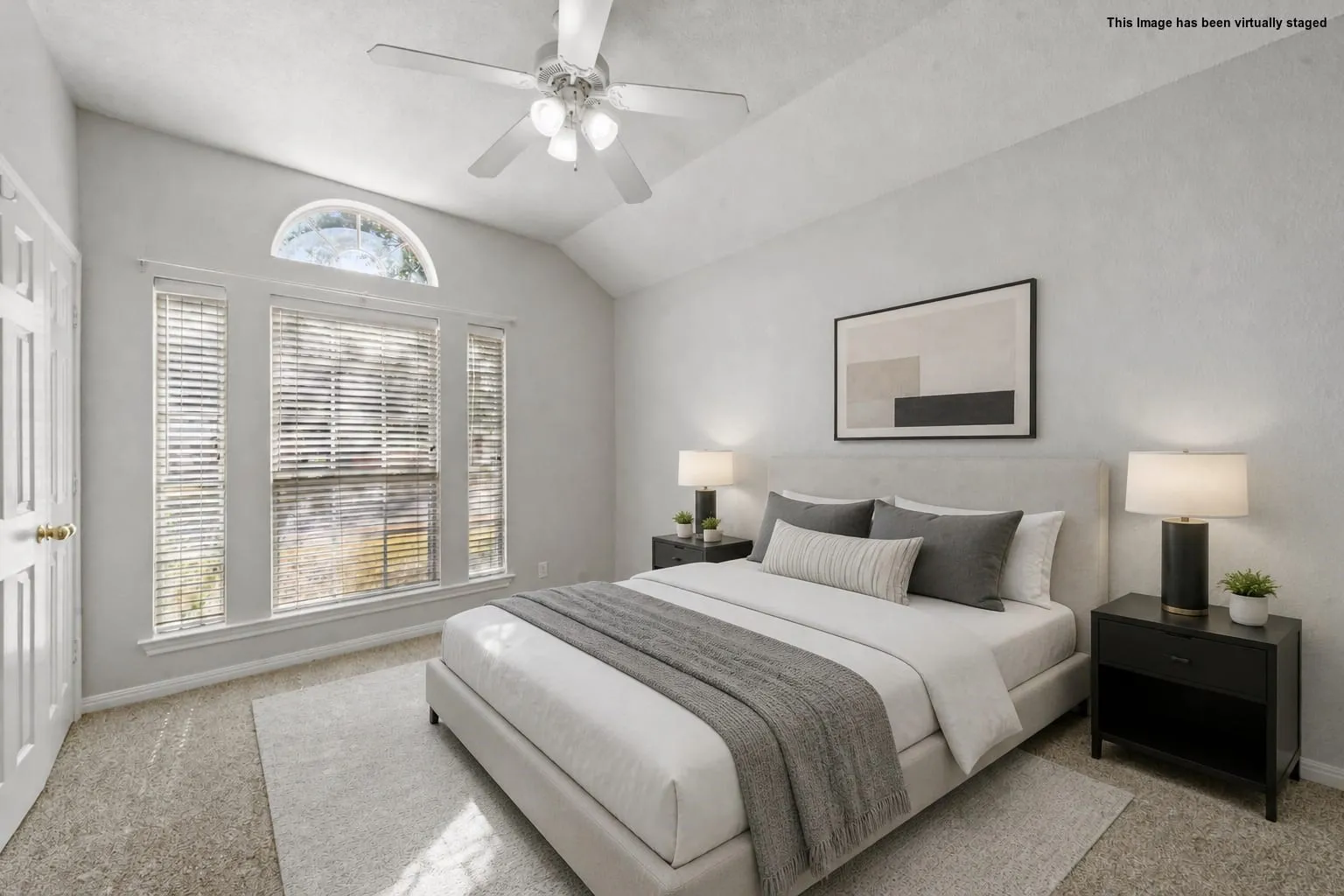 Vaulted ceiling, ceiling fan, arched transom window, large window array, and neutral carpeting
