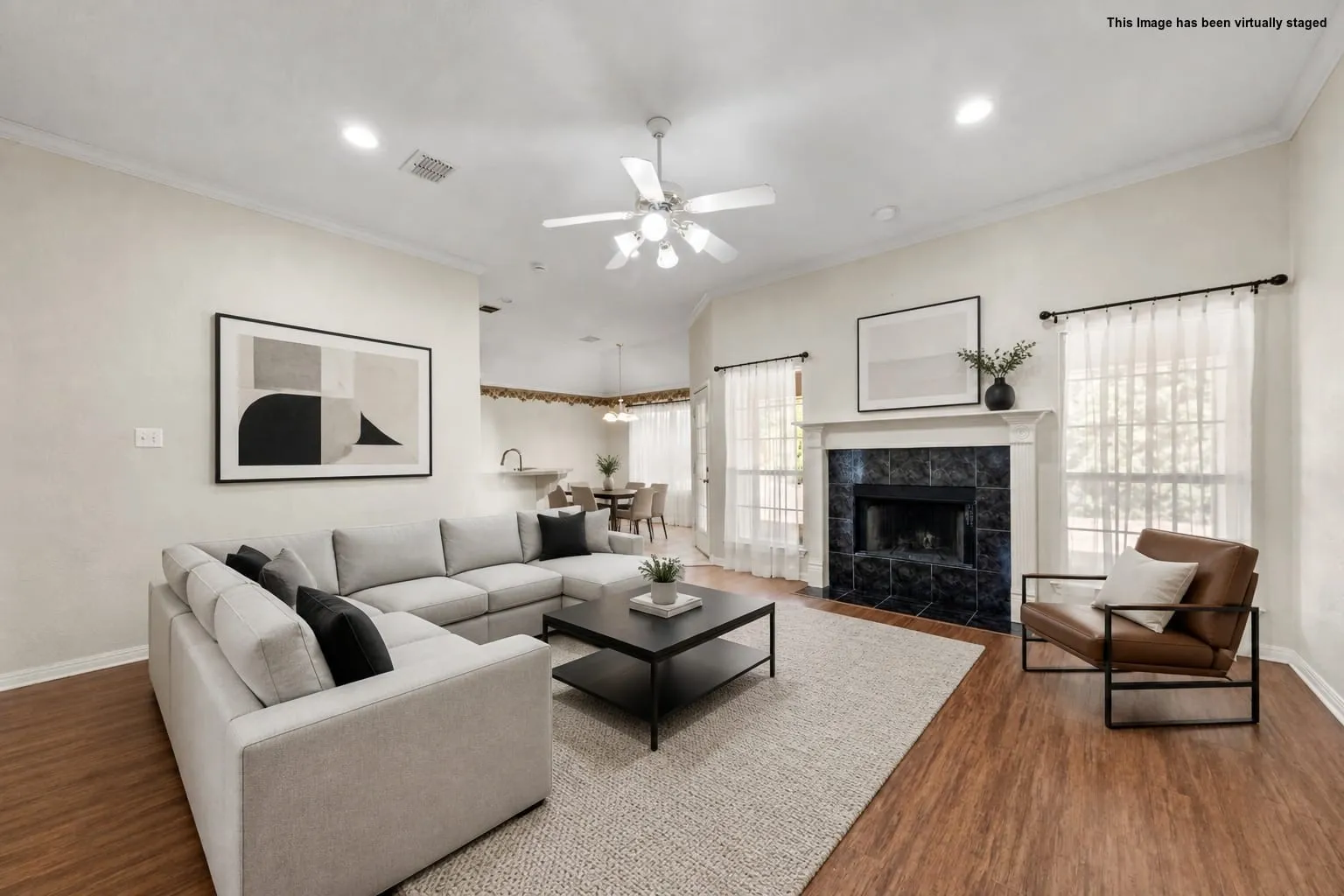 Vaulted ceilings, wood-finish flooring, recessed lighting, ceiling fan, and a fireplace with a black tile surround and a white mantel
