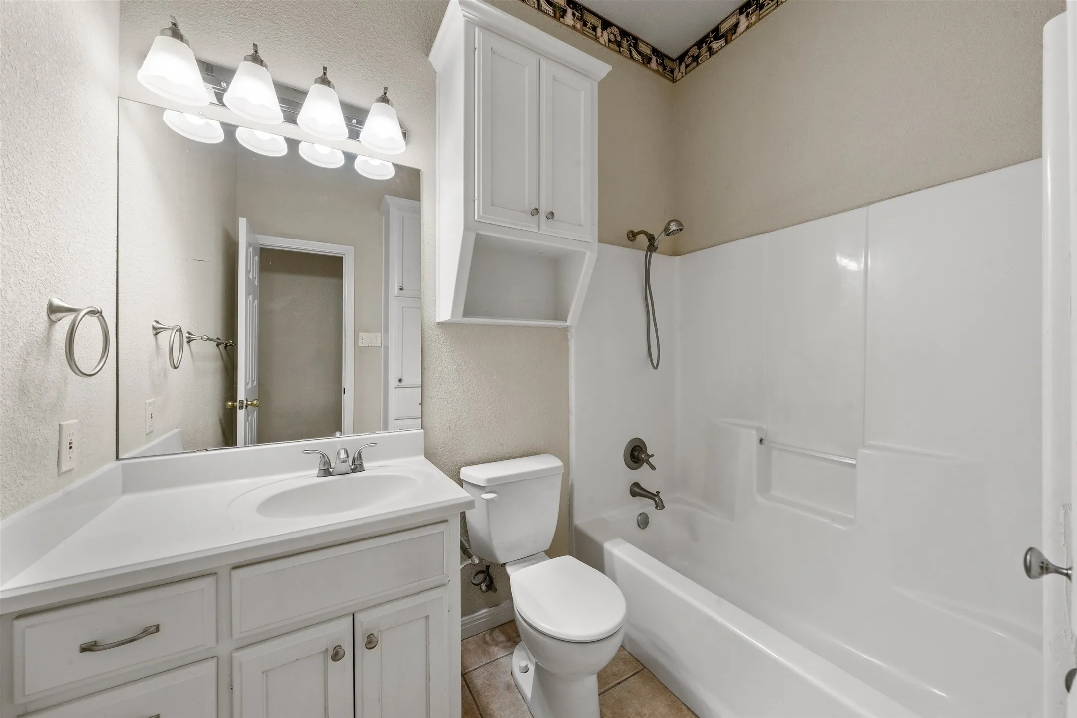 Bathroom featuring a single vanity with storage cabinetry, integrated sink, and a four-light fixture