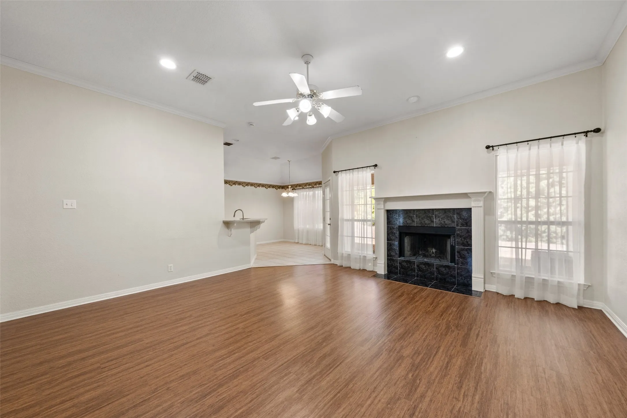 Vaulted ceiling with recessed lighting, wood-finish flooring, and a fireplace featuring dark tile surround