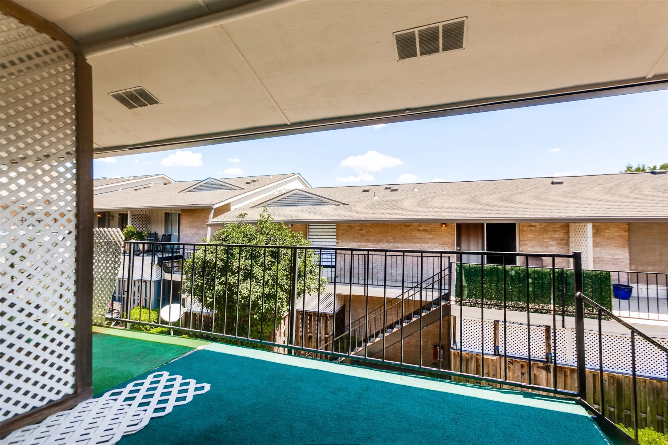 Covered balcony with white lattice privacy screen and outdoor carpet