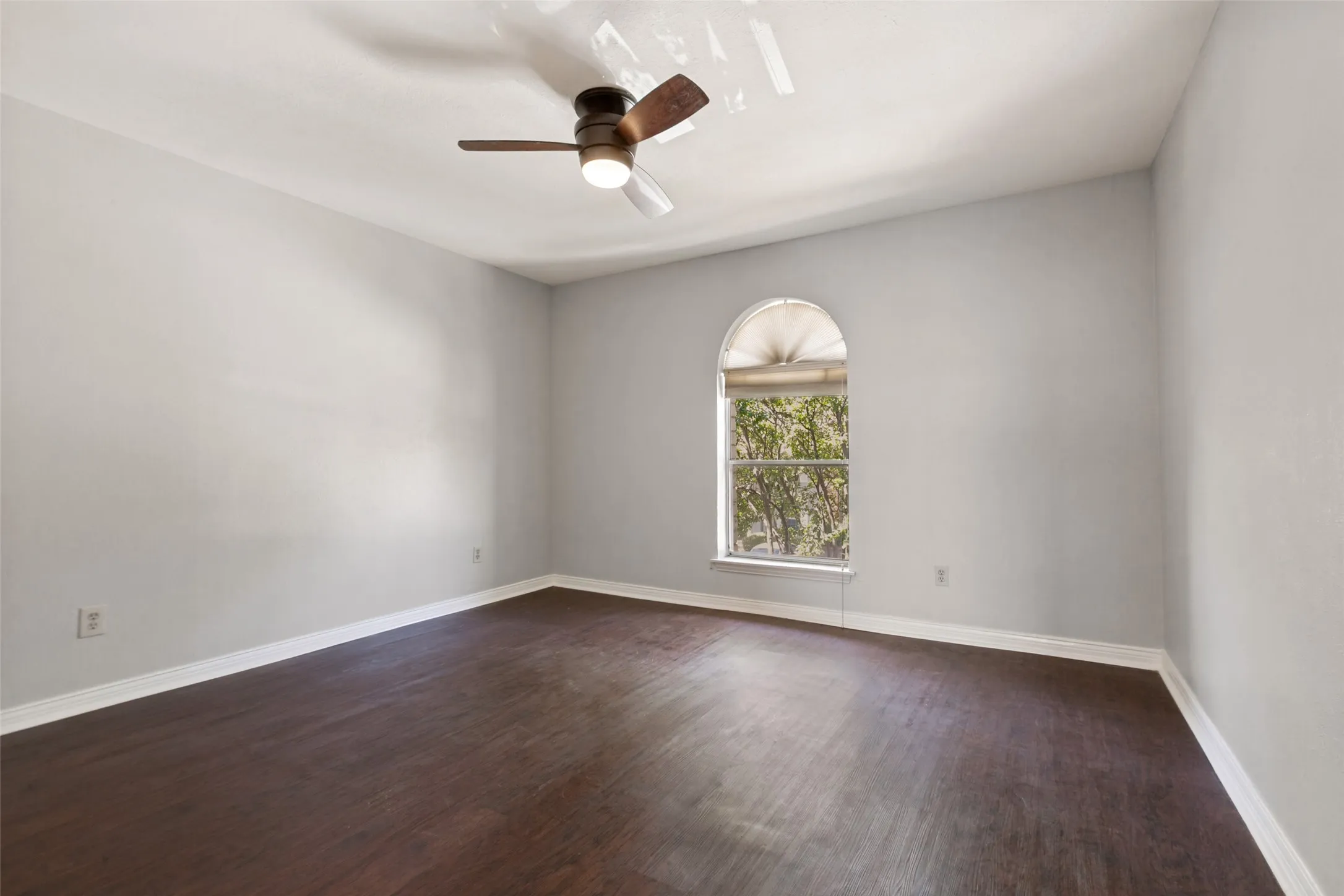 Spacious interior with dark wood-finish flooring, vaulted ceiling, and an arched window