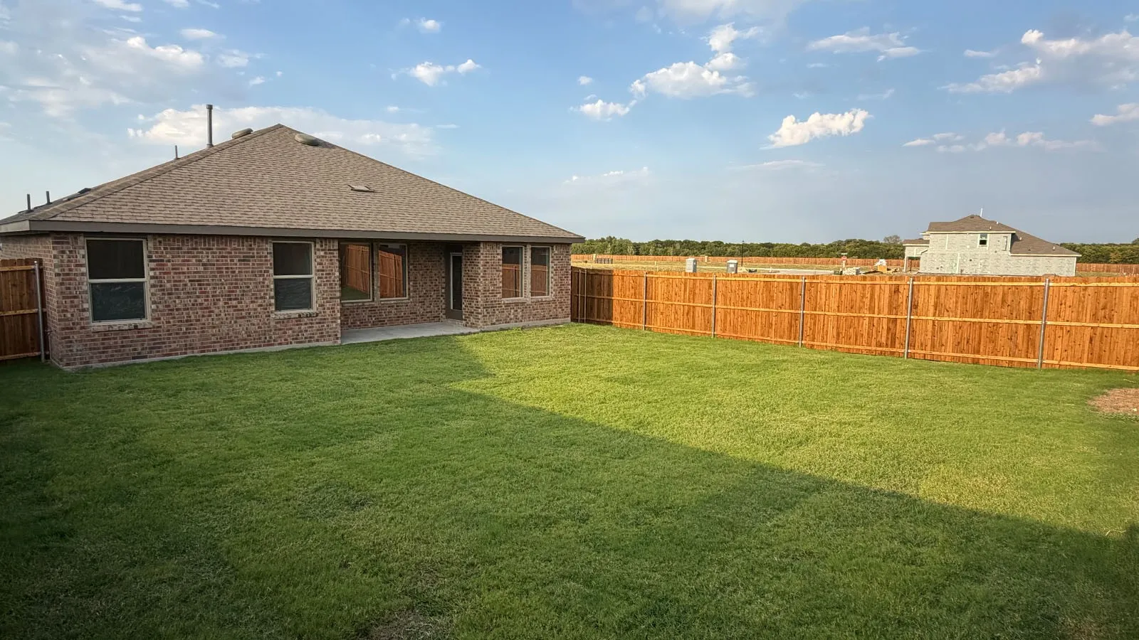 Expansive grassy lawn with a wood privacy fence
