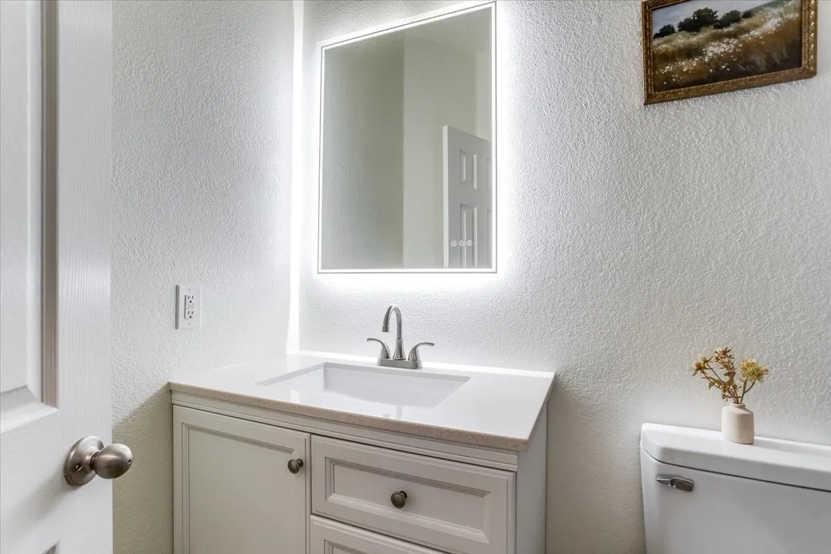 White vanity with under-mount sink, light-toned countertop, and brushed nickel faucet