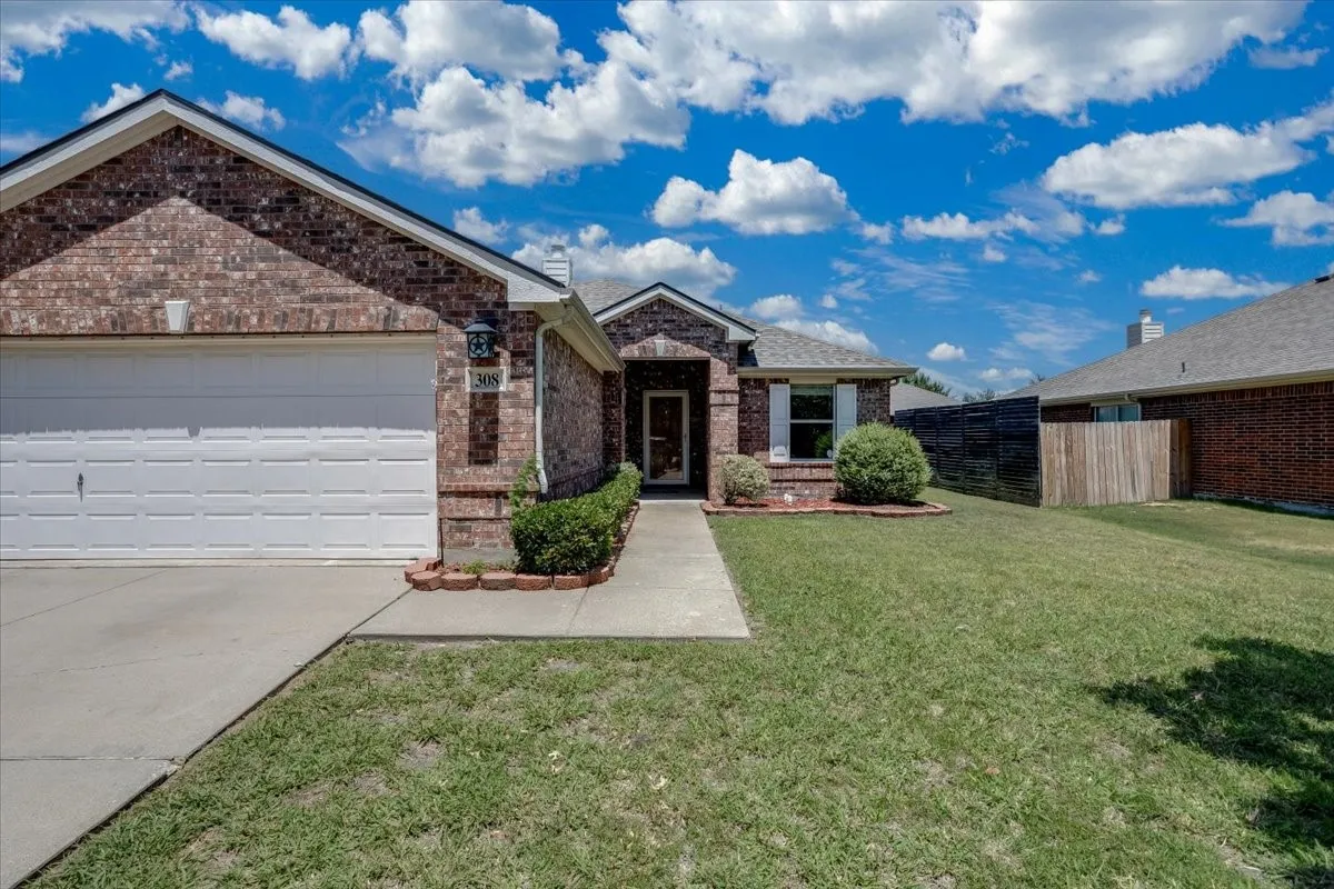 Brick exterior with an attached garage, paved driveway, and a front walkway