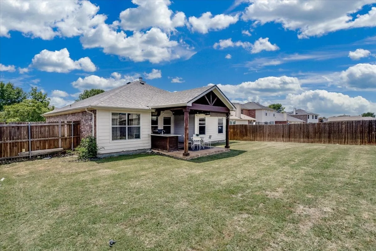 Expansive backyard featuring a covered patio, a built-in outdoor cooking area, and a privacy fence