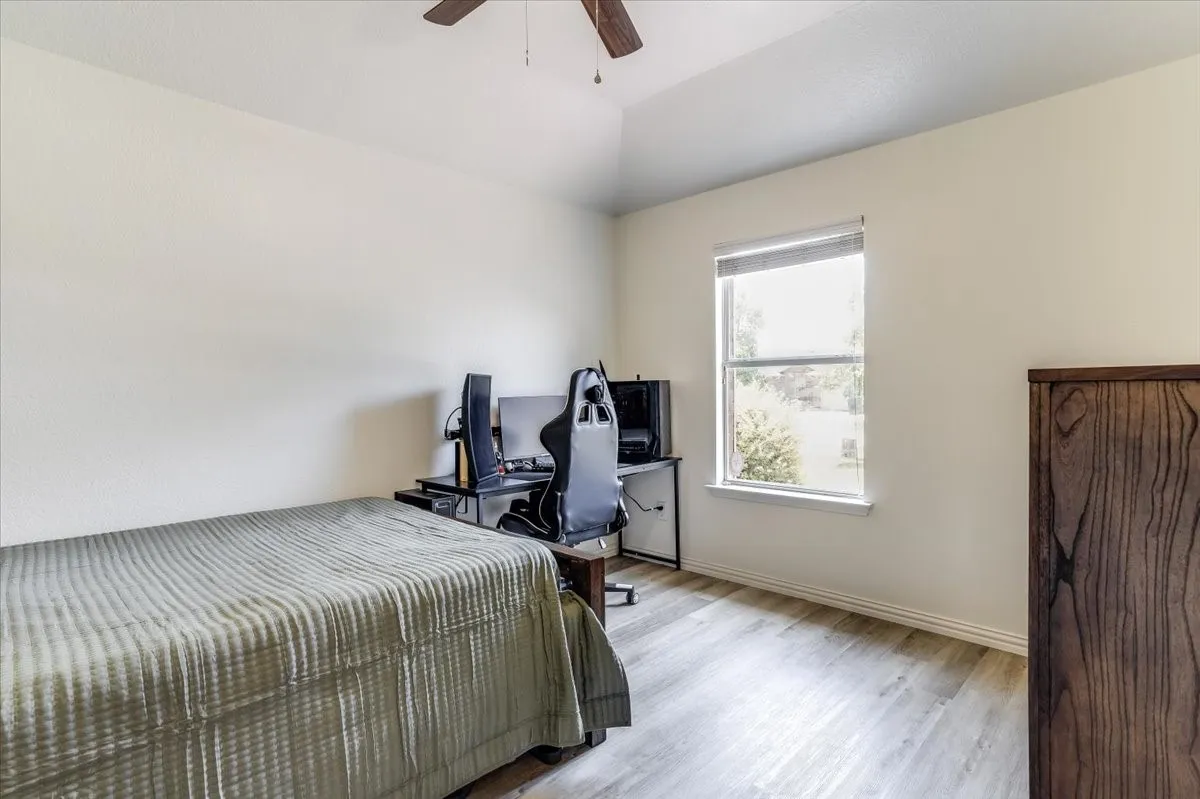 Vaulted ceiling, wood-finish flooring, ceiling fan, and a double-hung window