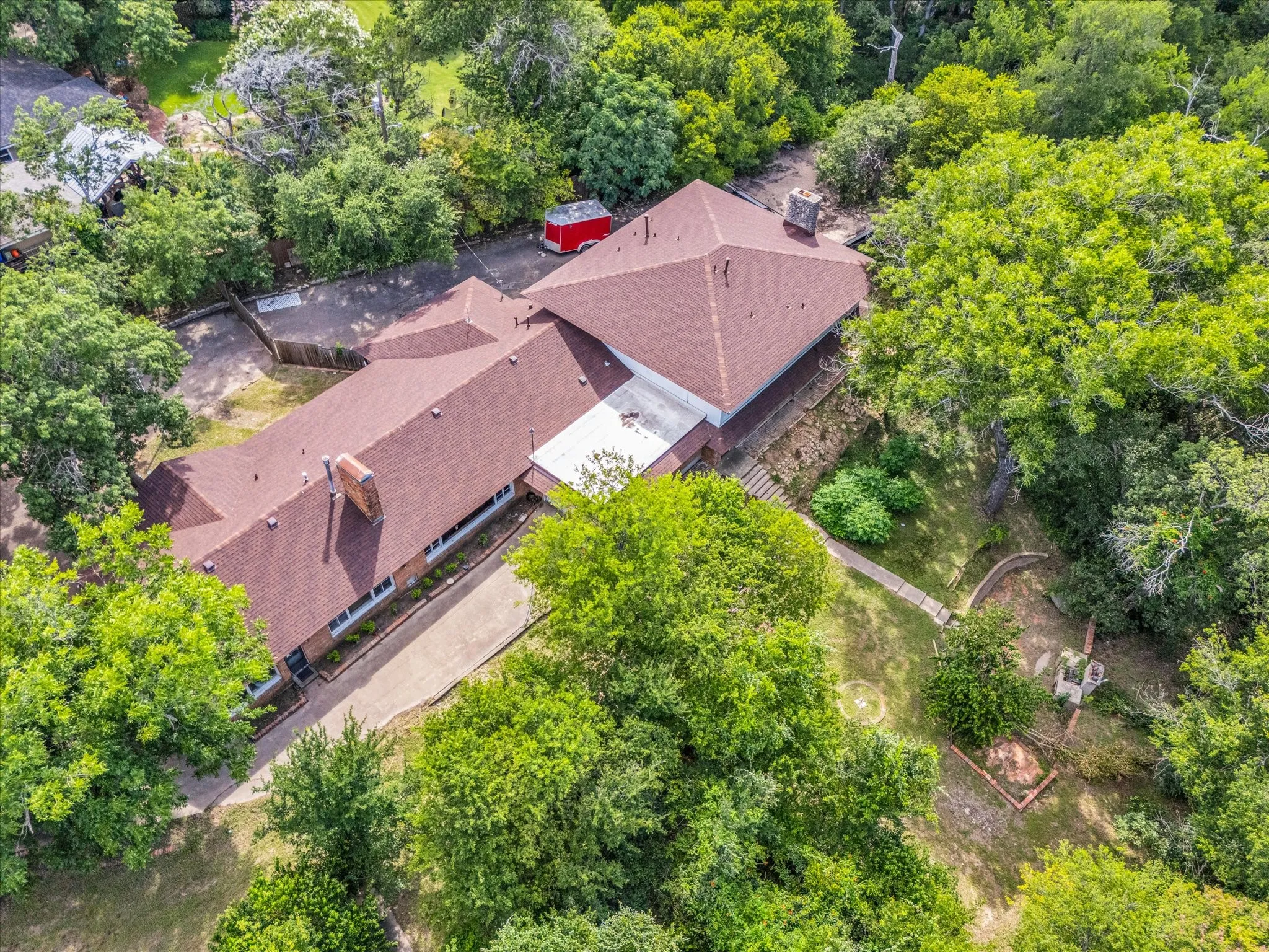Expansive property featuring a multi-gabled roofline, mature trees, and a concrete driveway