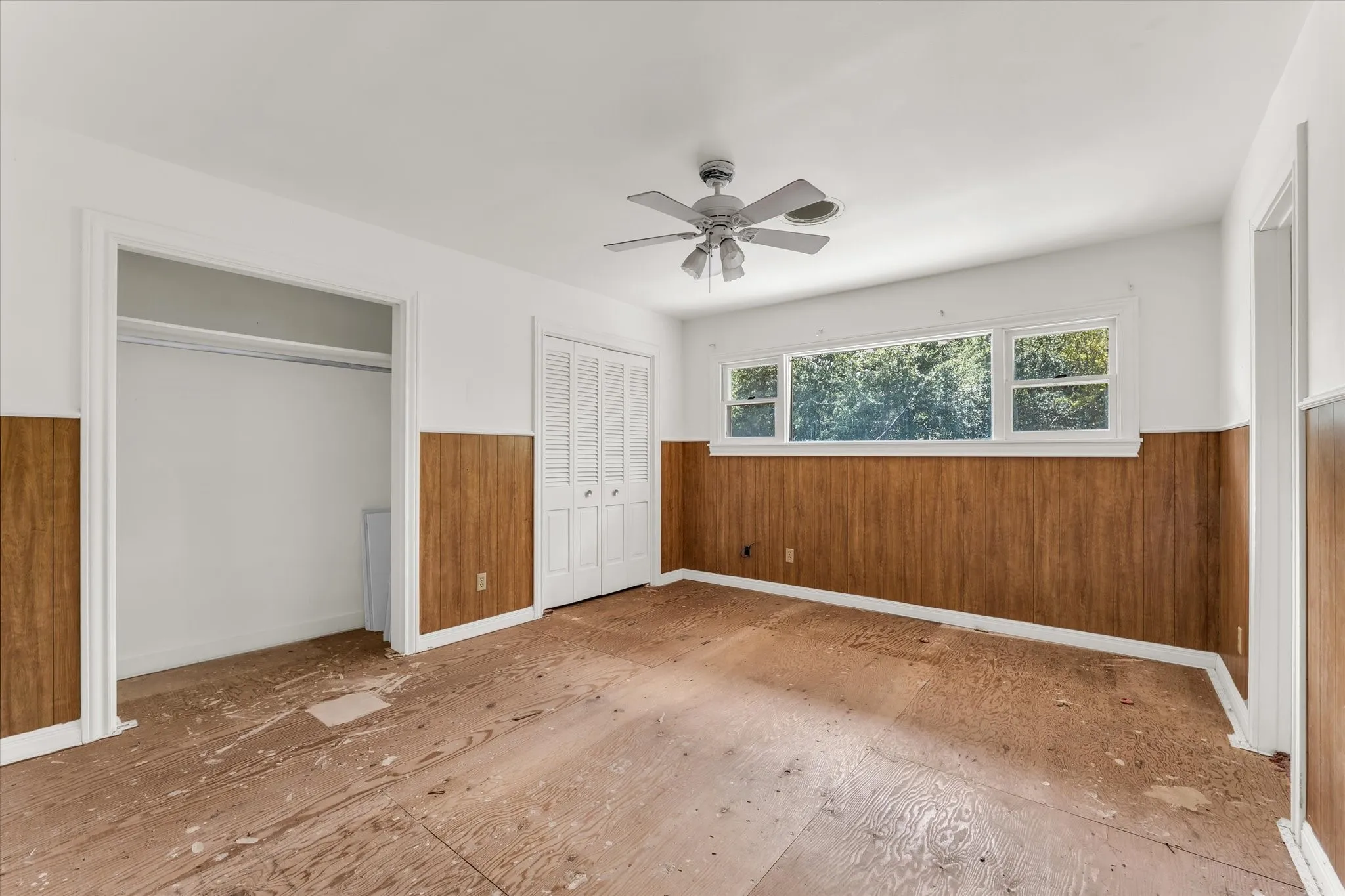 Upstairs 1st bedroom on the left, wood paneling, multiple windows, ceiling fan, bi-fold closet doors, additional closet space