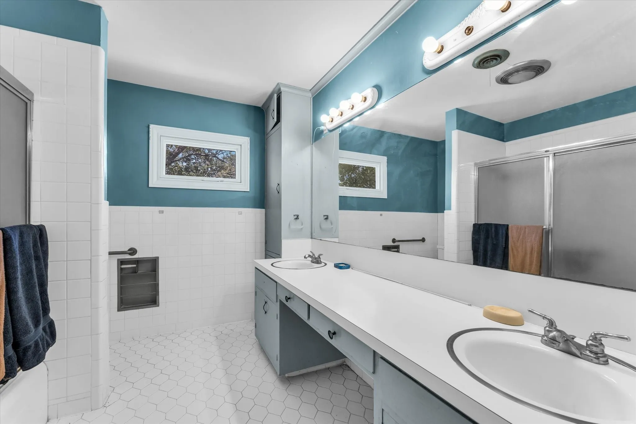 Upstairs Master bathroom dual vanity with integrated sinks, full-width mirror, and overhead strip lighting