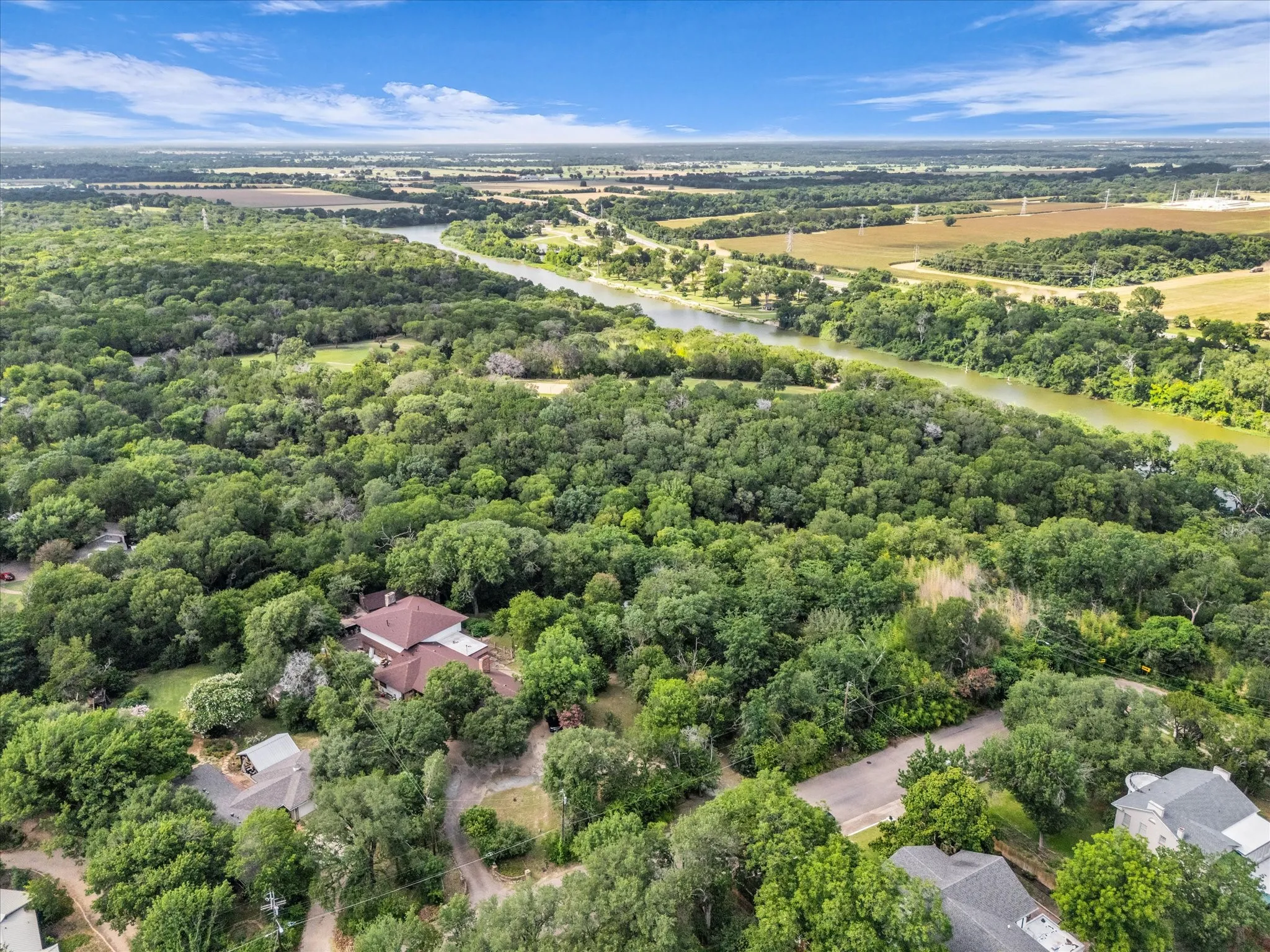 Expansive property featuring dense tree coverage, a natural water body, and surrounding agricultural land