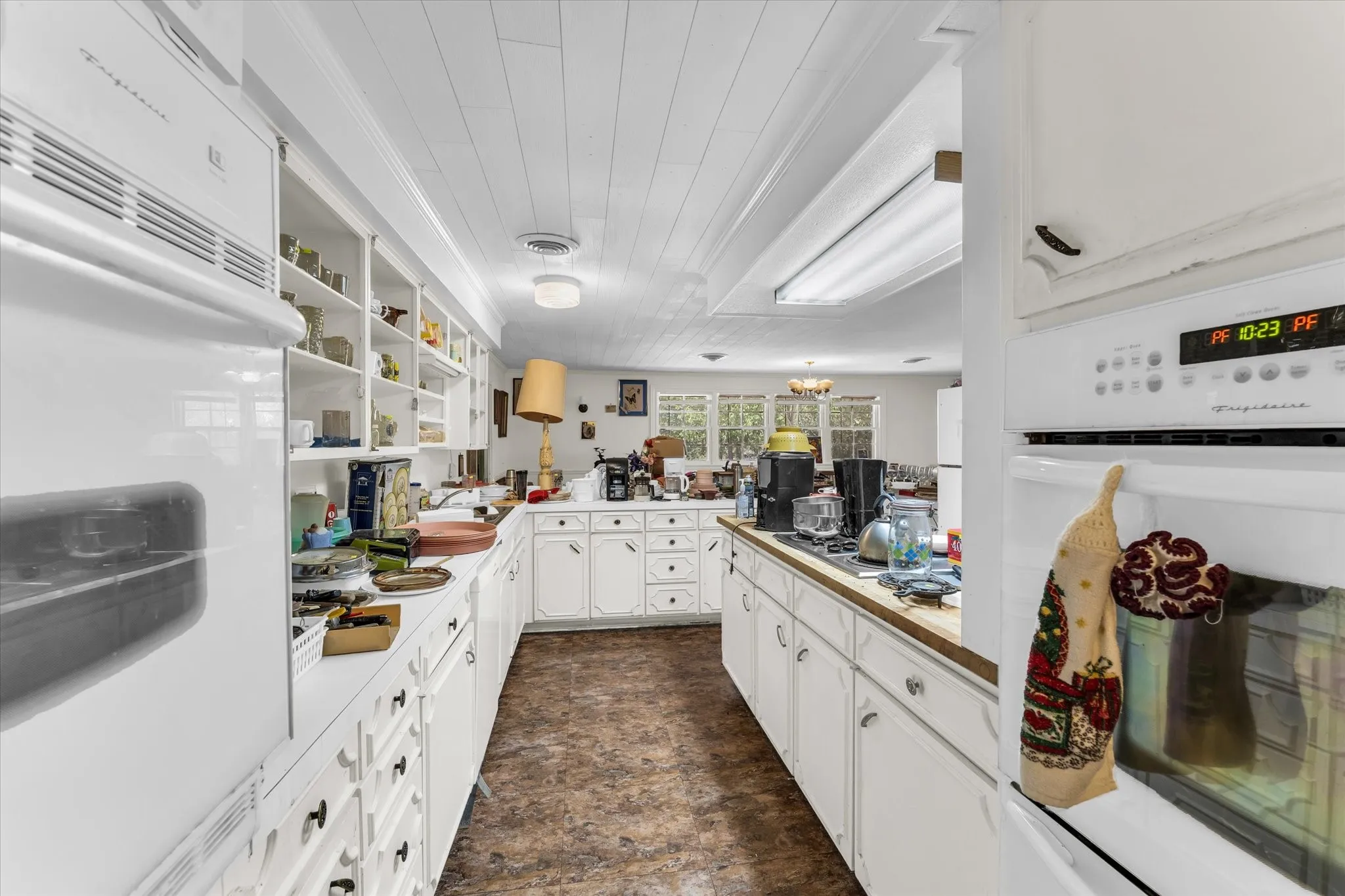 Galley kitchen featuring white cabinetry, built-in wall oven, and white appliances