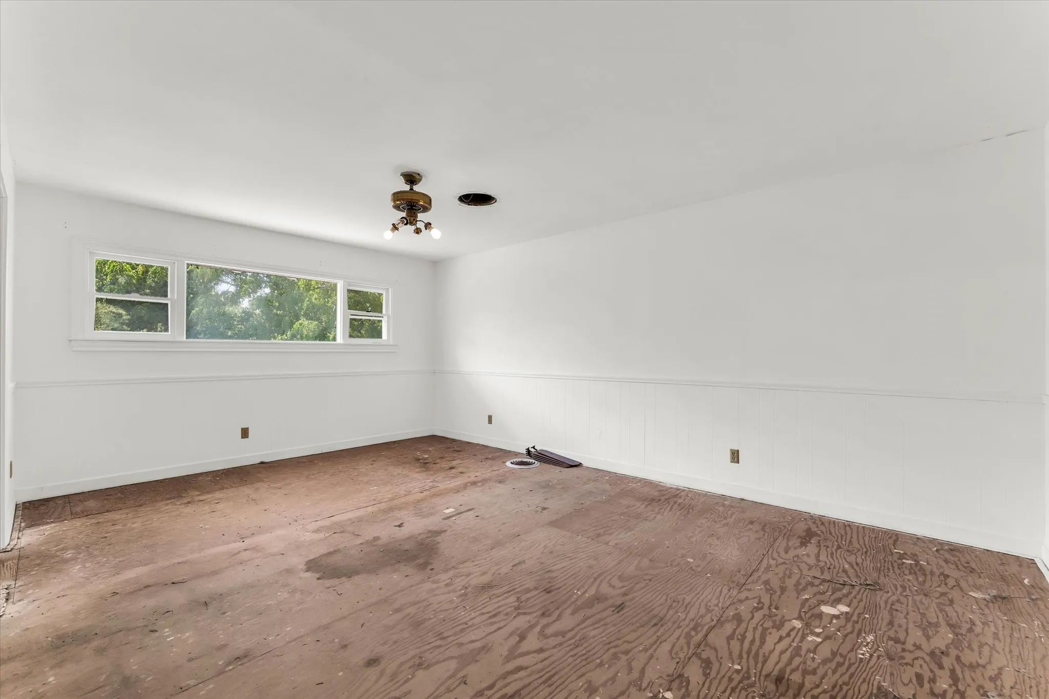 Upstair stairs, at the end of the hallway Bedroom suite, with its own bathroom, white walls with a chair rail and paneling, multiple windows, and a ceiling-mounted light fixture