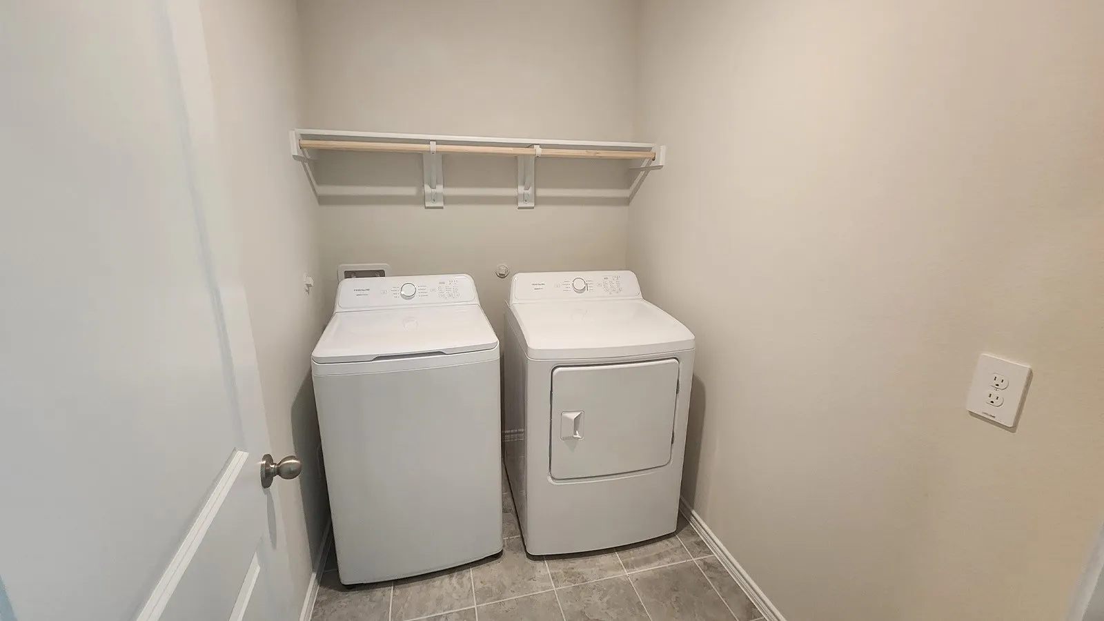 Laundry area featuring tile flooring, a wall-mounted clothes rod, and a neutral wall color