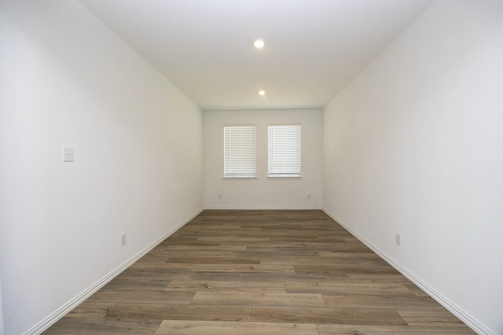 Recessed ceiling lighting illuminates wood-finish flooring
