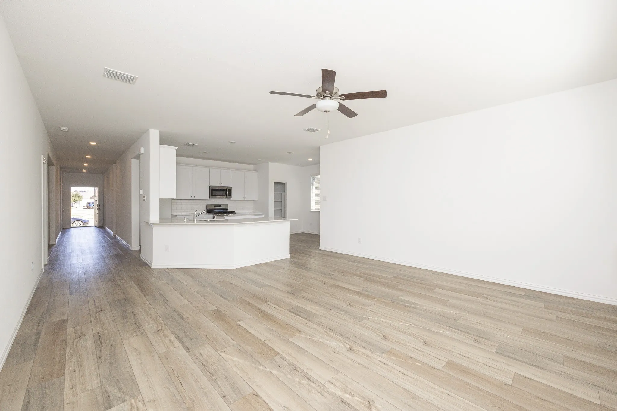 Open-concept living area with wood-finish flooring, recessed lighting, and a ceiling fan