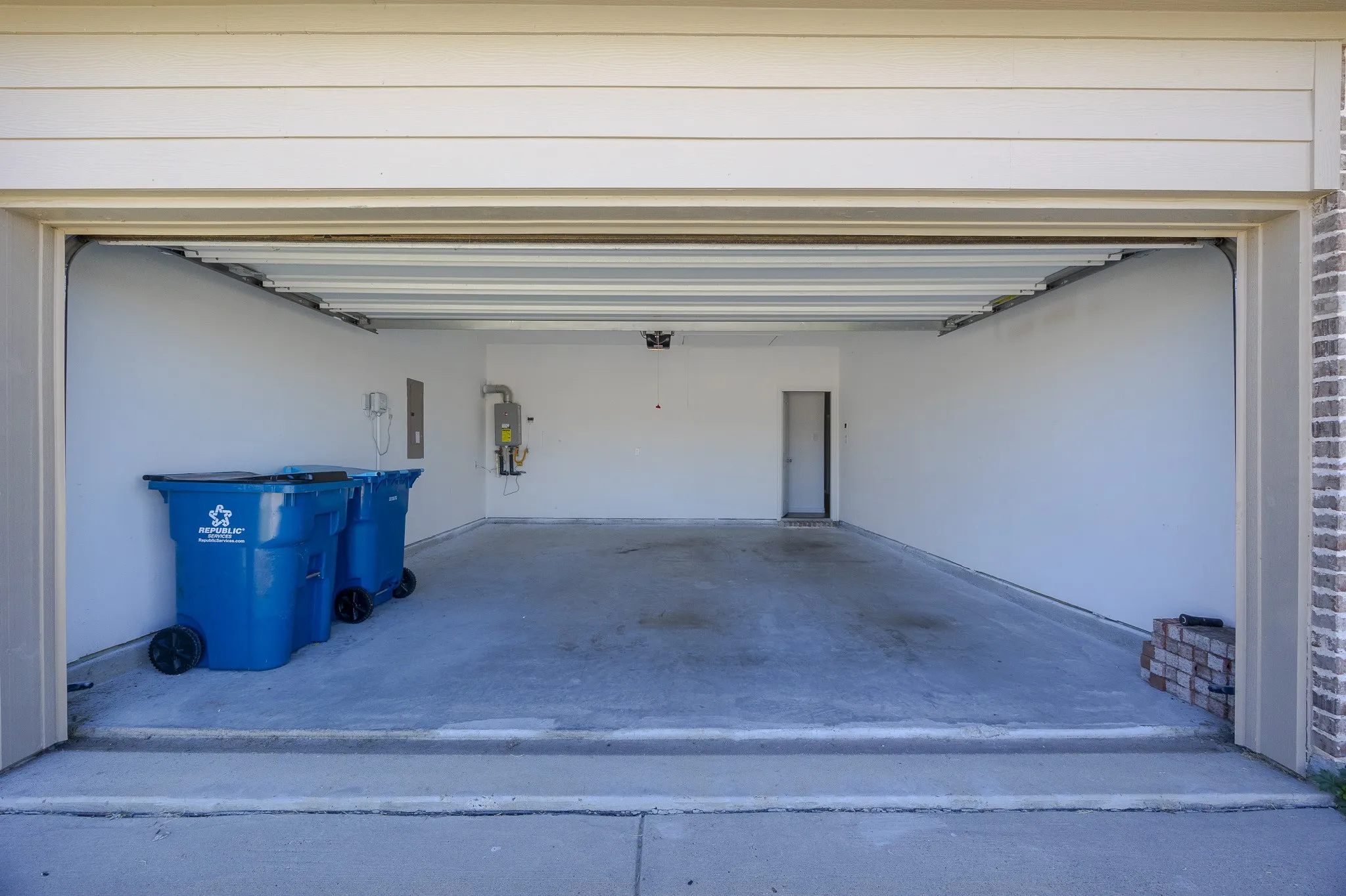Two-car garage featuring a concrete floor, painted interior walls, a built-in water heater, and an interior access door