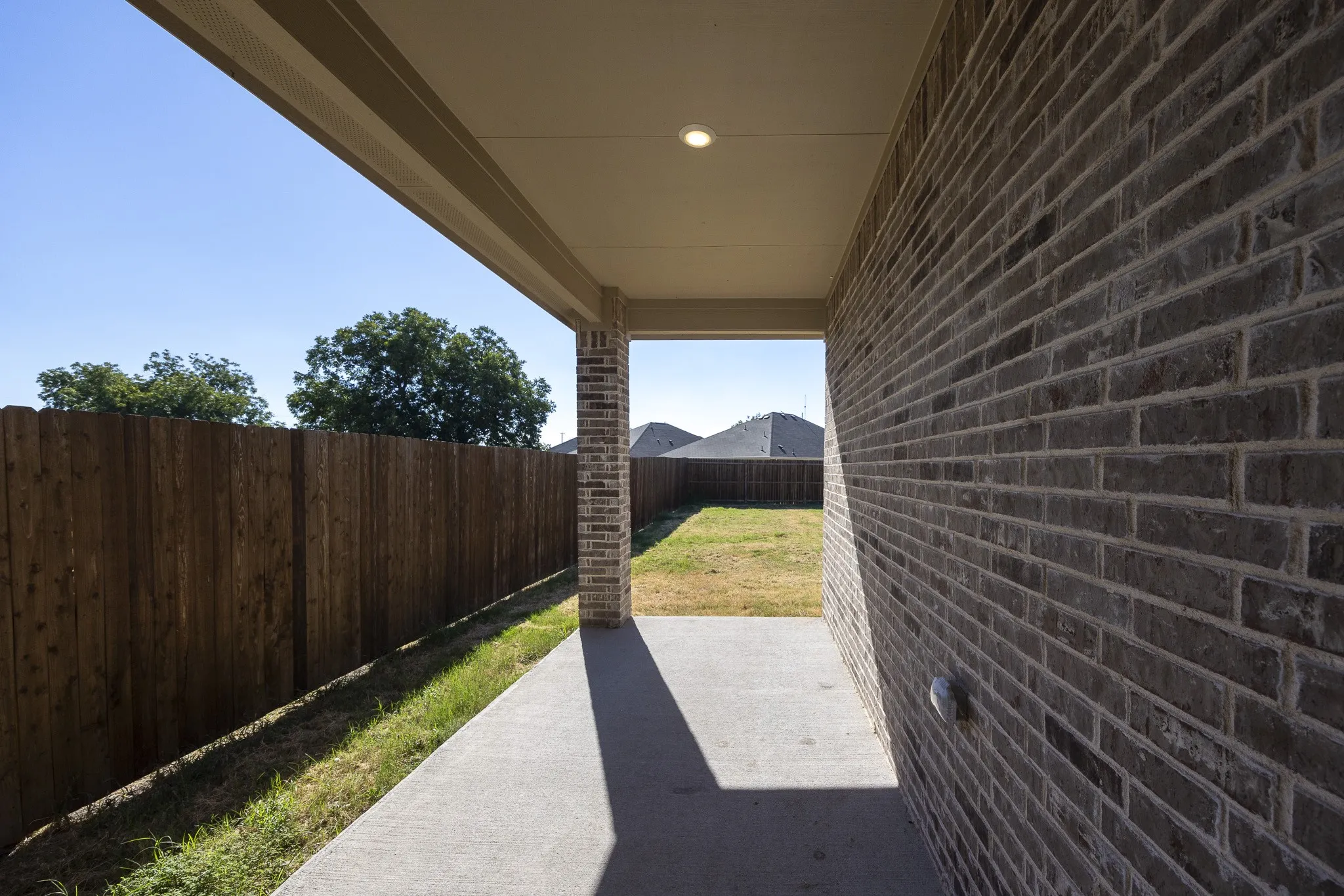 Covered patio featuring a recessed light, brick column, and a concrete slab