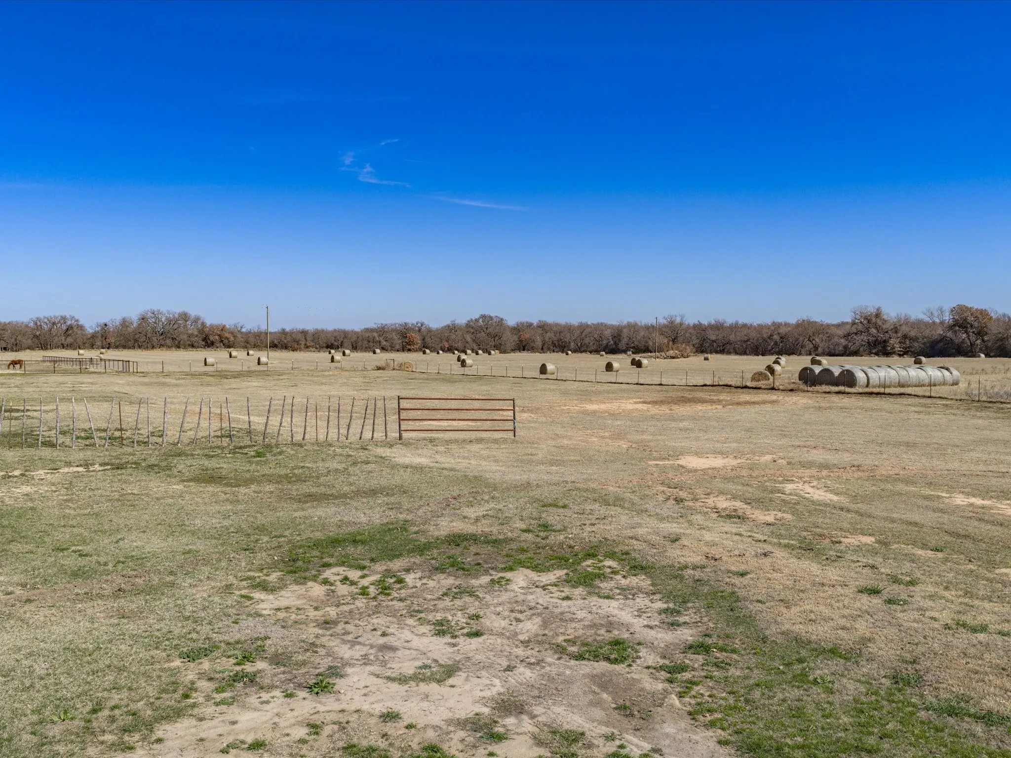 Expansive open field with partial fencing and distant tree line