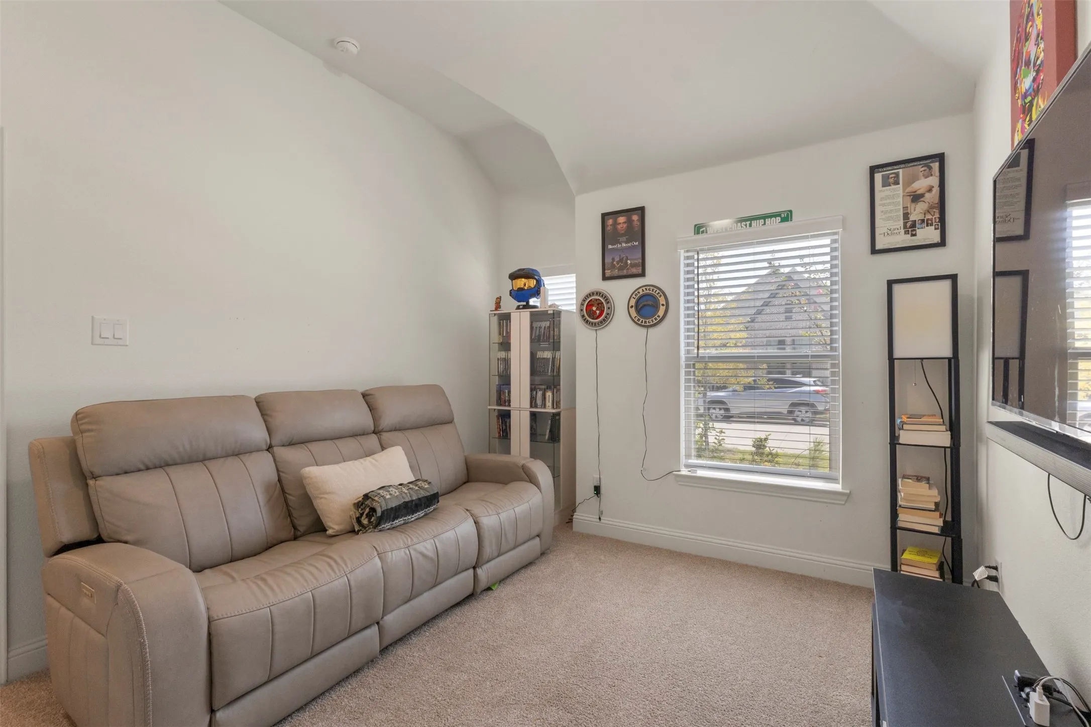 Carpeted room featuring a window with blinds, baseboards, and a built-in shelving unit