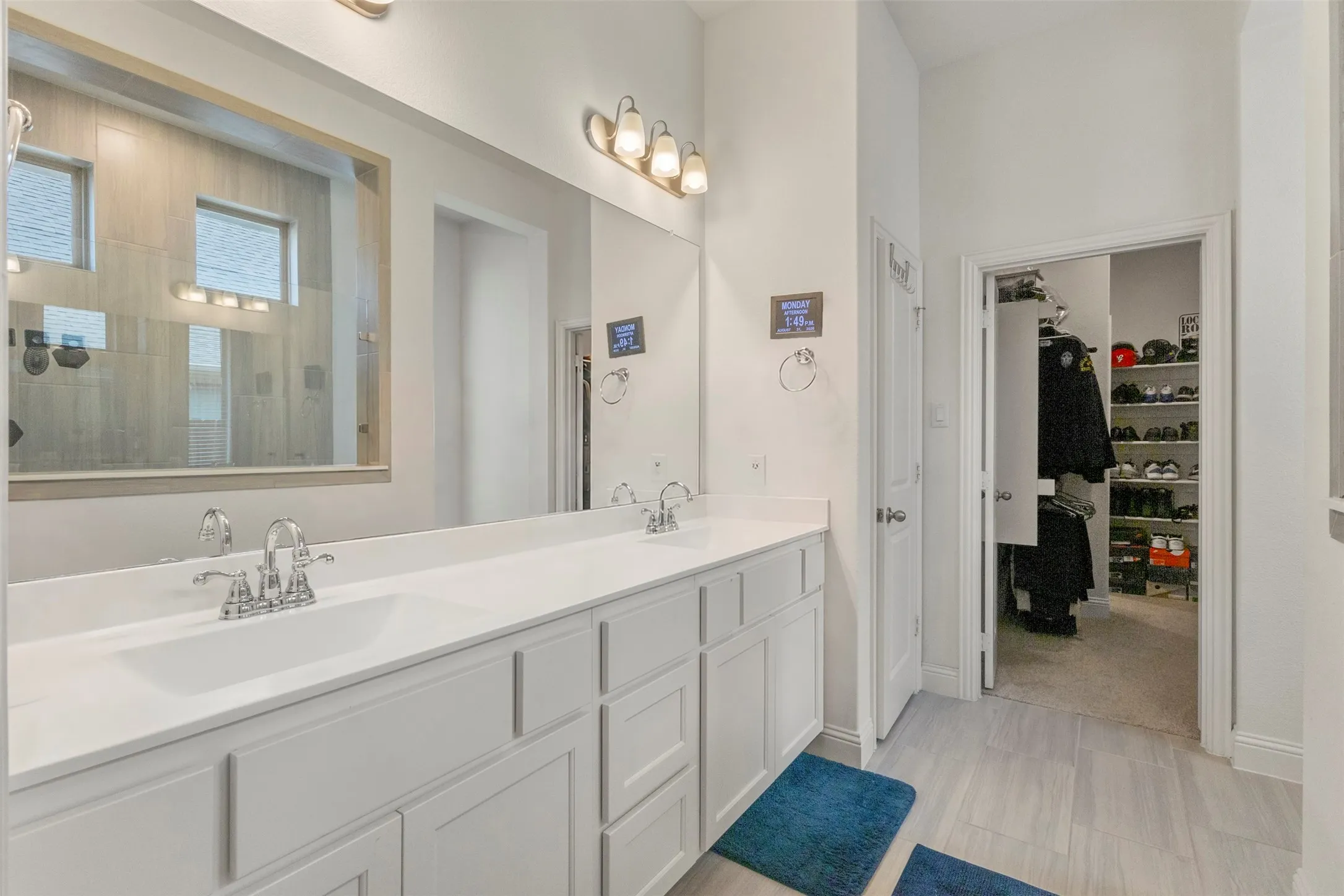 Dual vanity with white cabinetry, polished chrome fixtures, and a large mirror