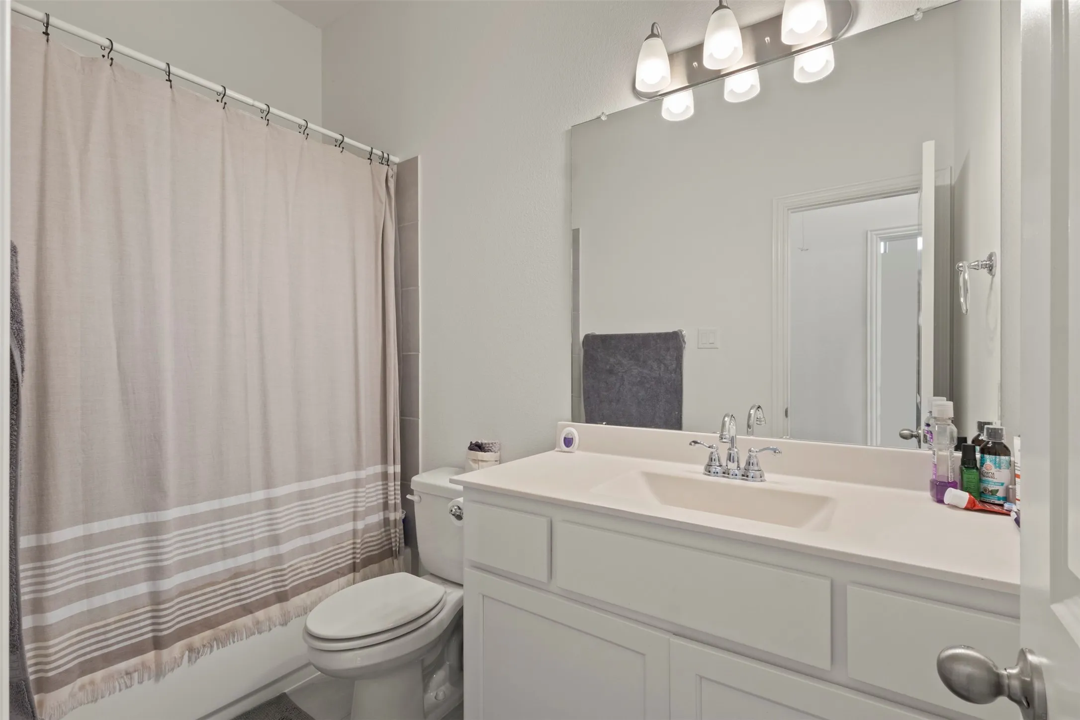 White vanity with an integrated sink, polished chrome faucet, and a large wall-mounted mirror