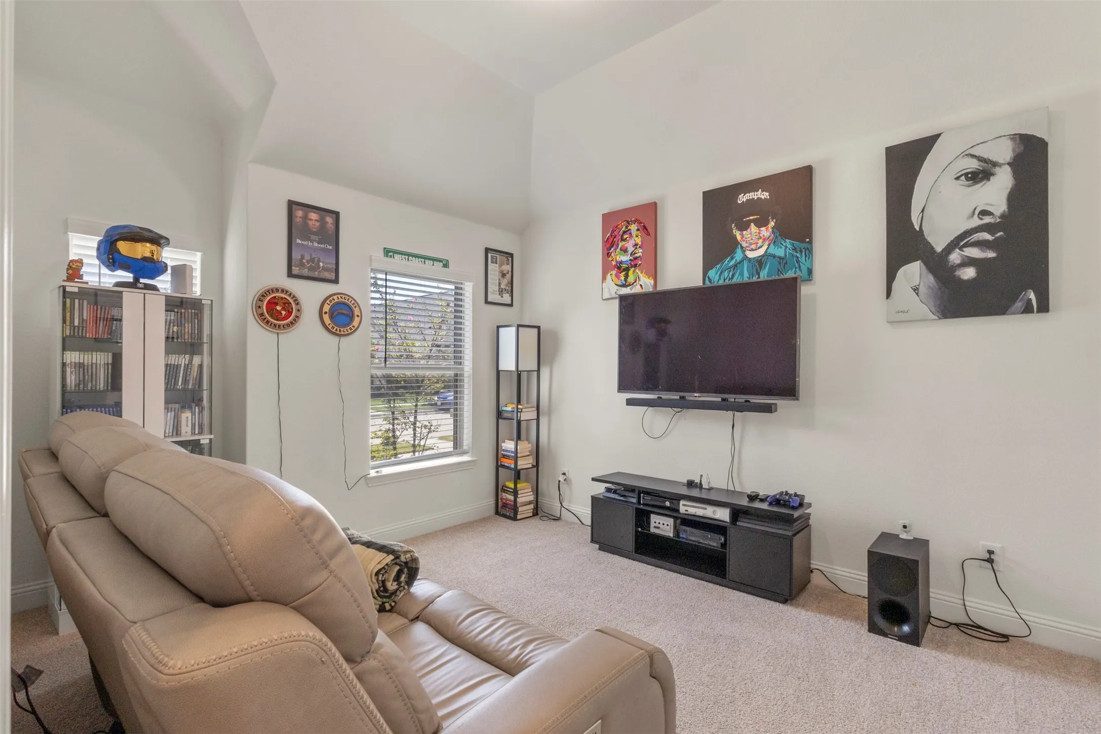 Carpeted room featuring dual windows with horizontal blinds, a media wall, and a vaulted ceiling