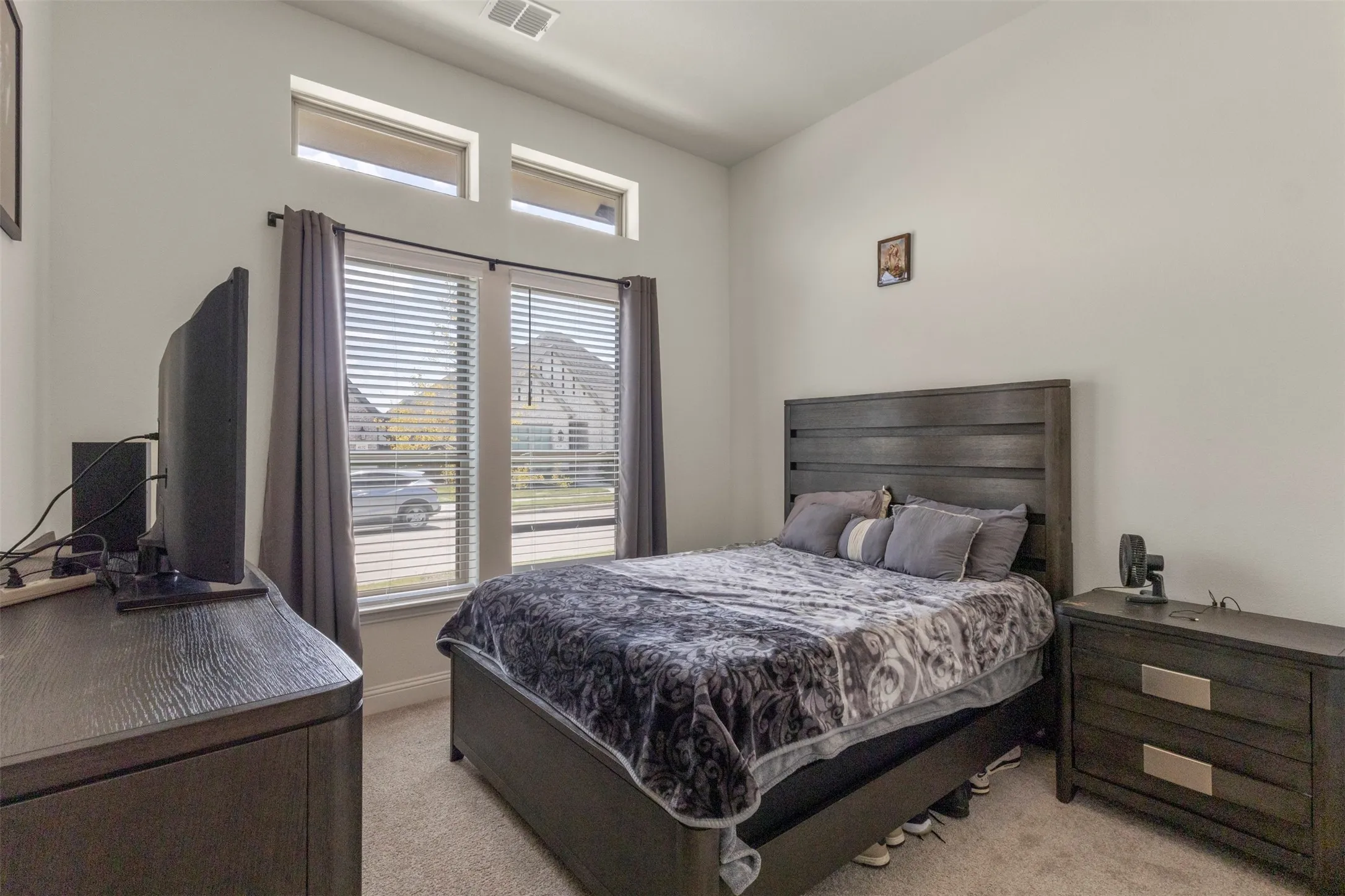 Carpeted room featuring a large window with blinds and drapes, two upper transom windows, and light-colored walls